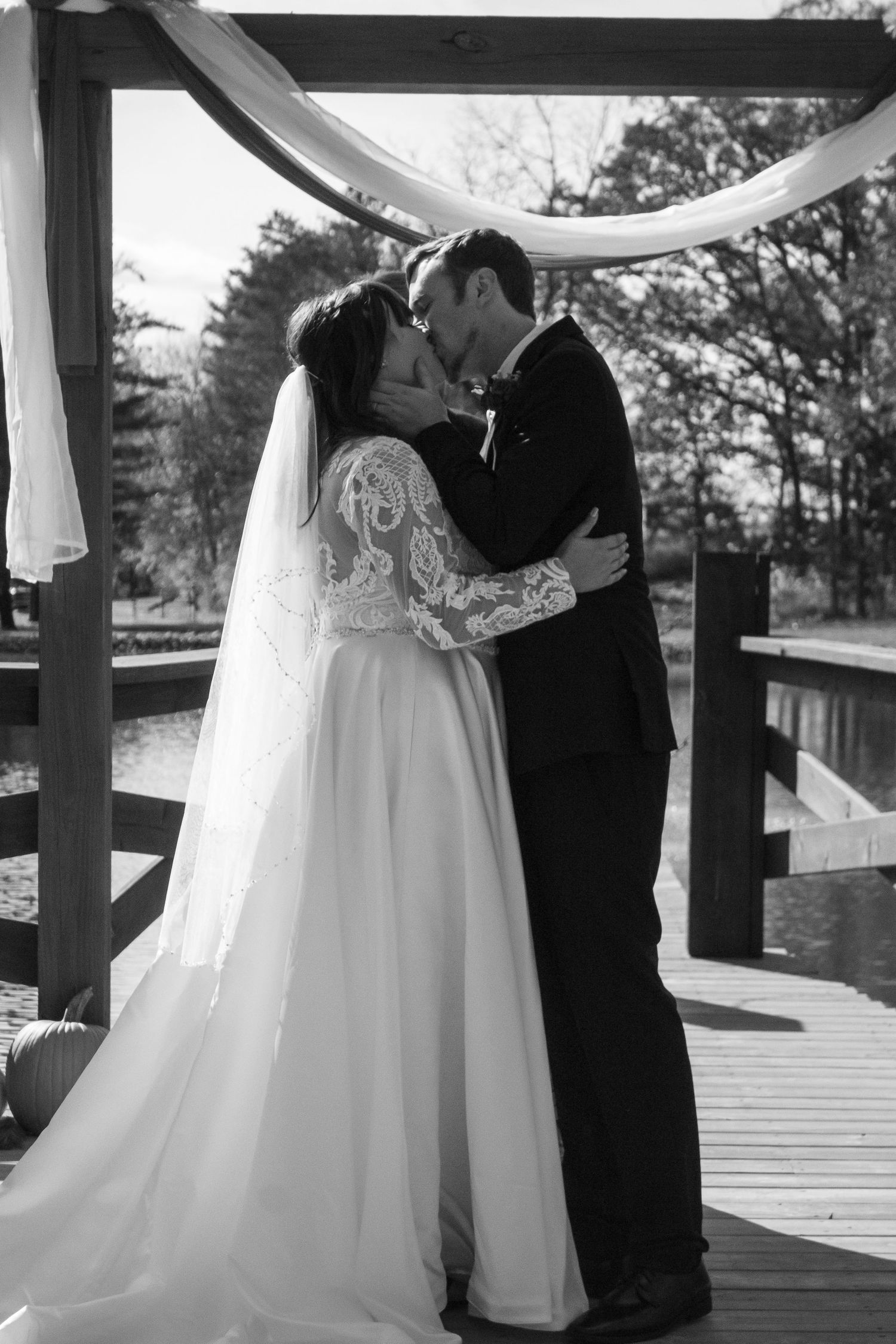 Romantic wedding couple embracing on wooden deck in black and white.