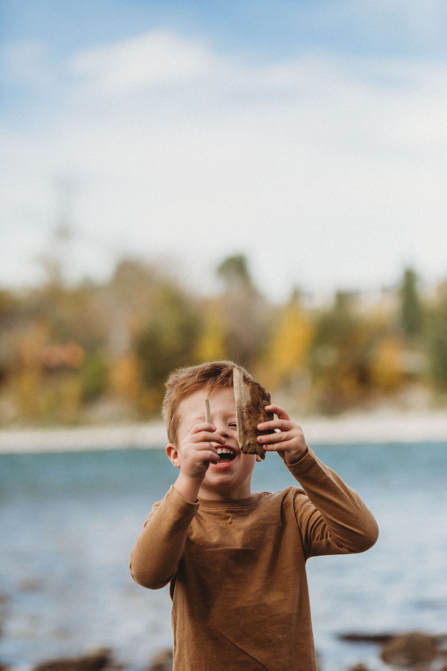 Boy finding sticks in a documentary style Calgary family photography session in Prince's Island Park