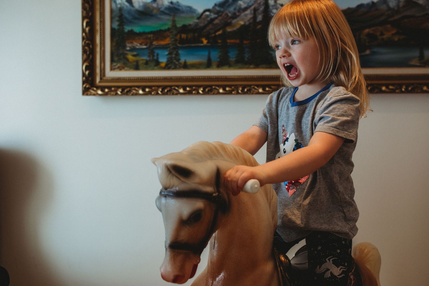 Girl riding a toy horse in an in-home Calgary family photography session.