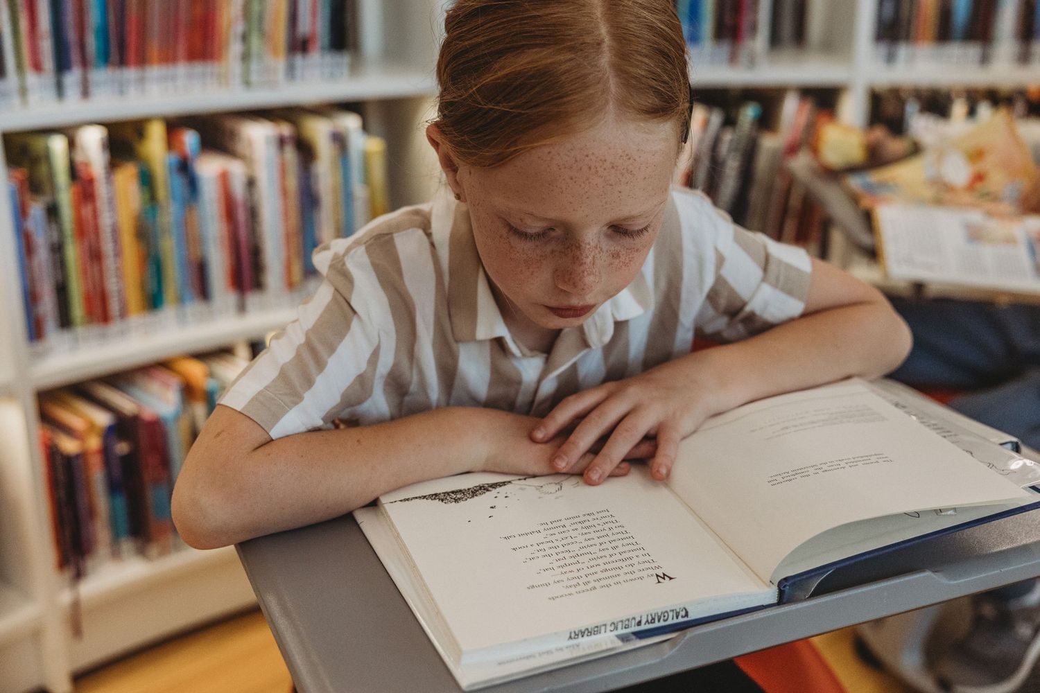 Girl reading a book in a Calgary family photography session at the Central Calgary Public Library.