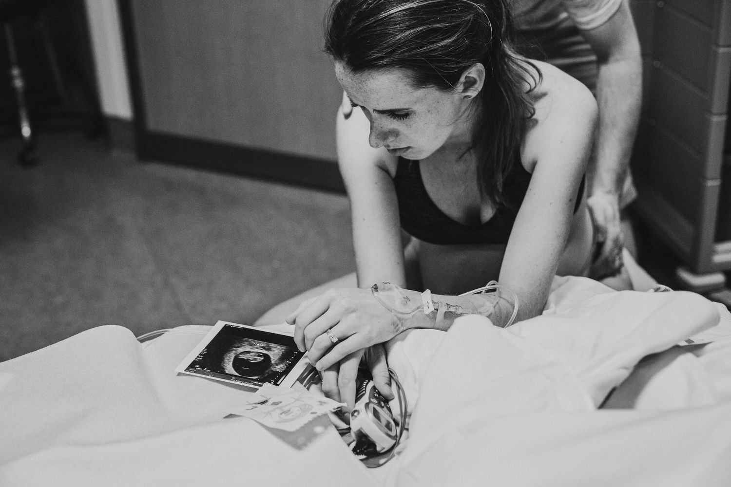 Mother looking at an ultrasound photo during labour at the Calgary South Health Campus. Calgary Birth Photographer.
