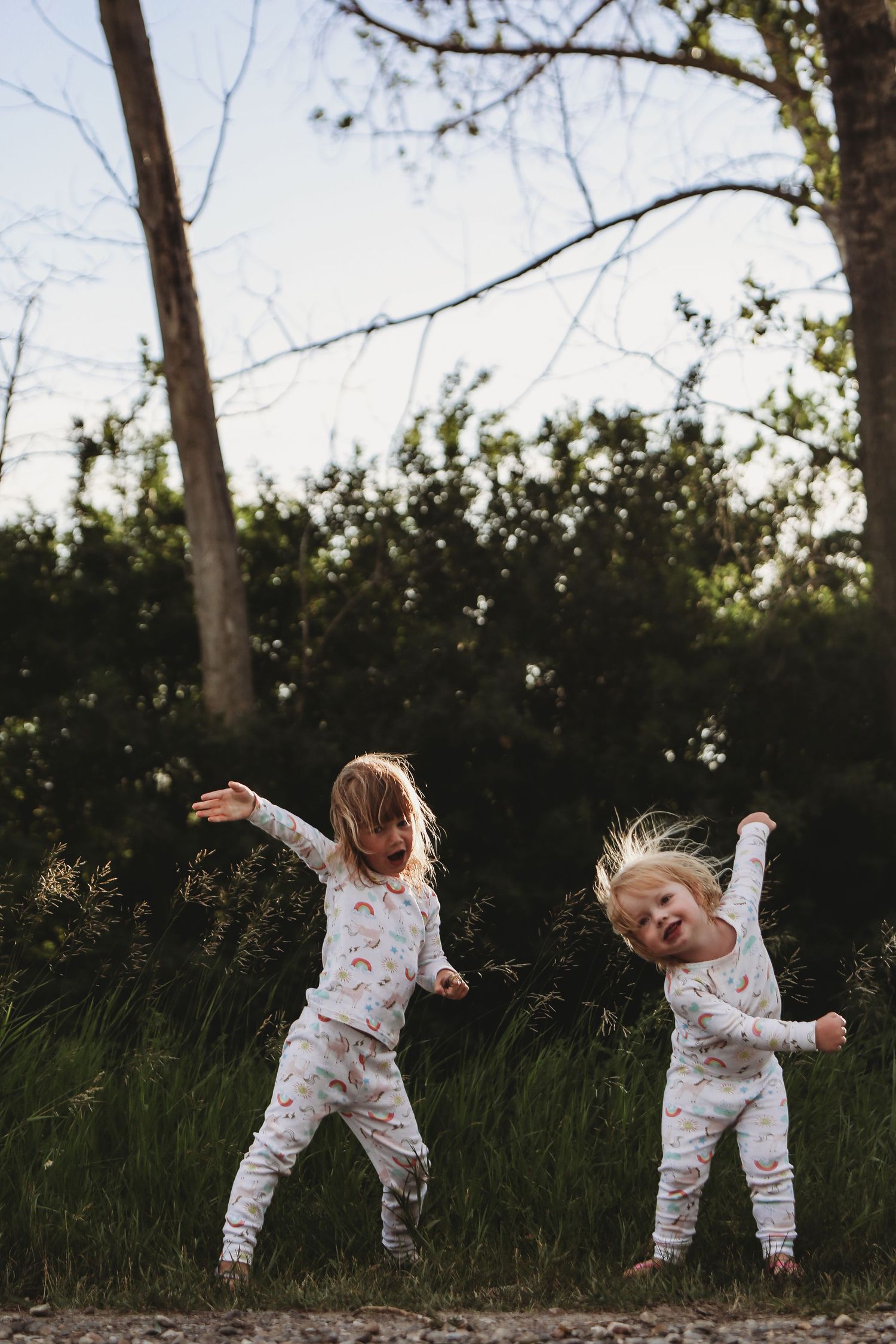 Girls dancing in pajamas in the evening light in an outdoor Calgary family photography session.