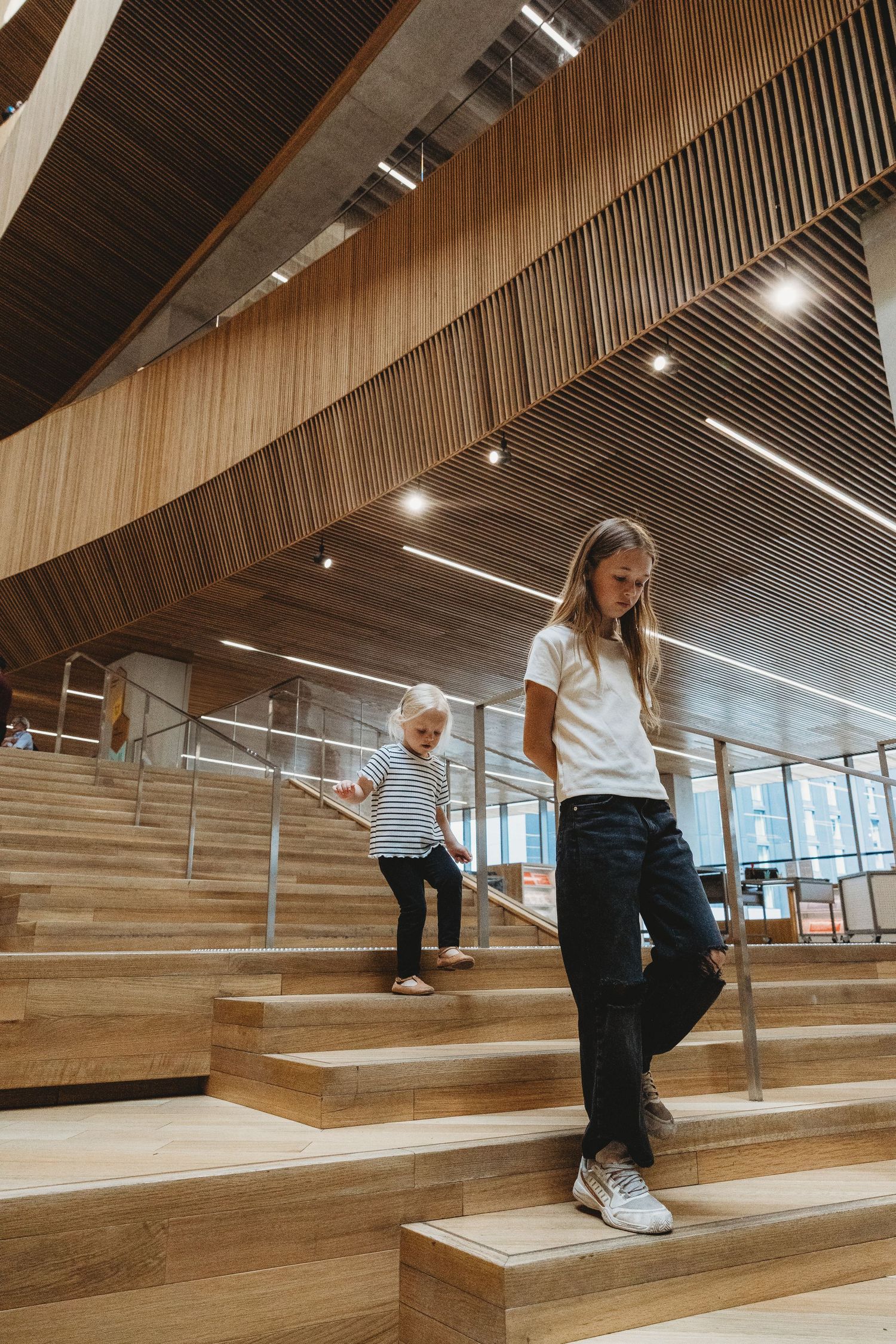 Sisters walking on the stairs in a Calgary family photography session at the Central Calgary Public Library.