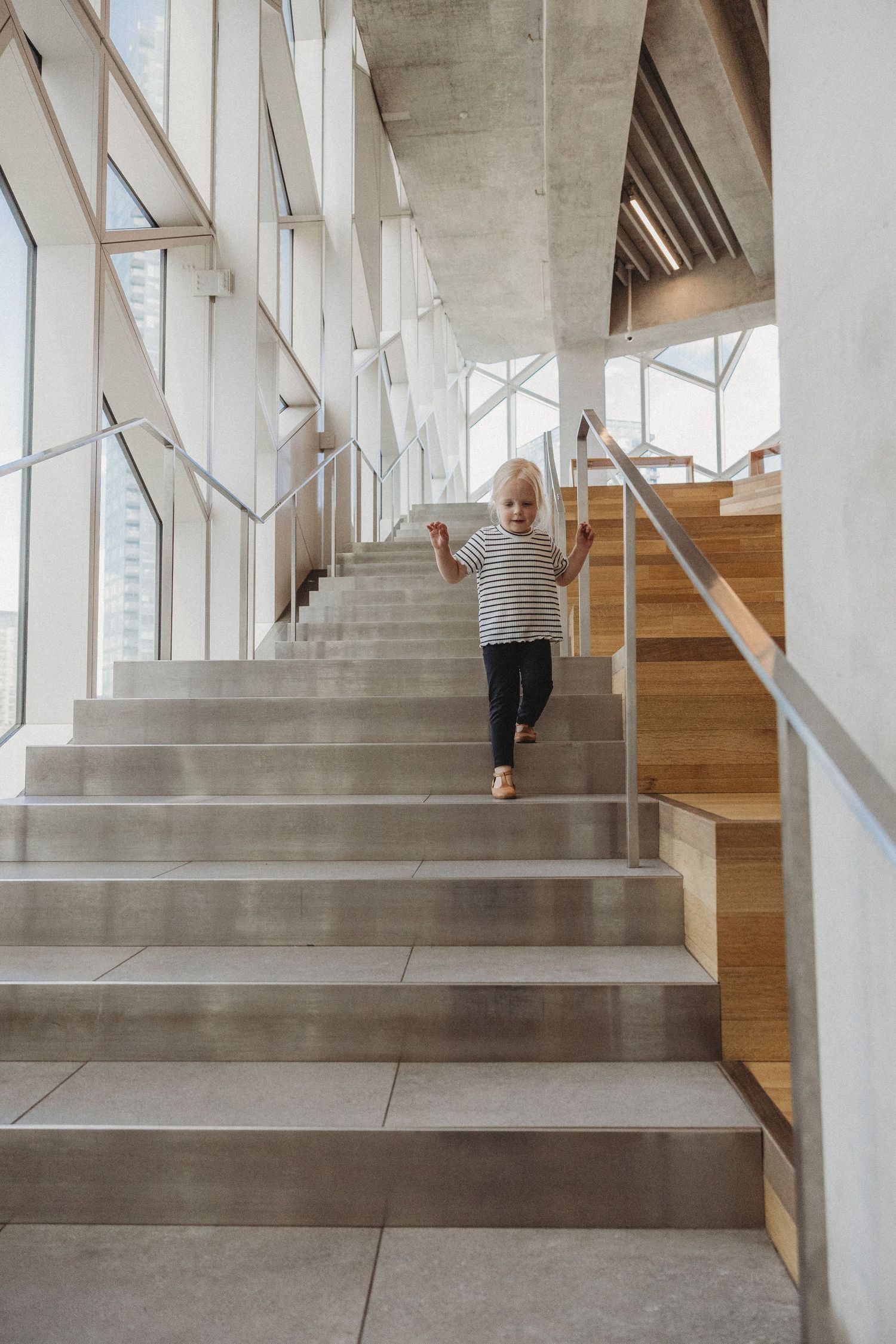 Toddler girl walking on the stairs in a Calgary family photography session at Central Calgary Public Library.
