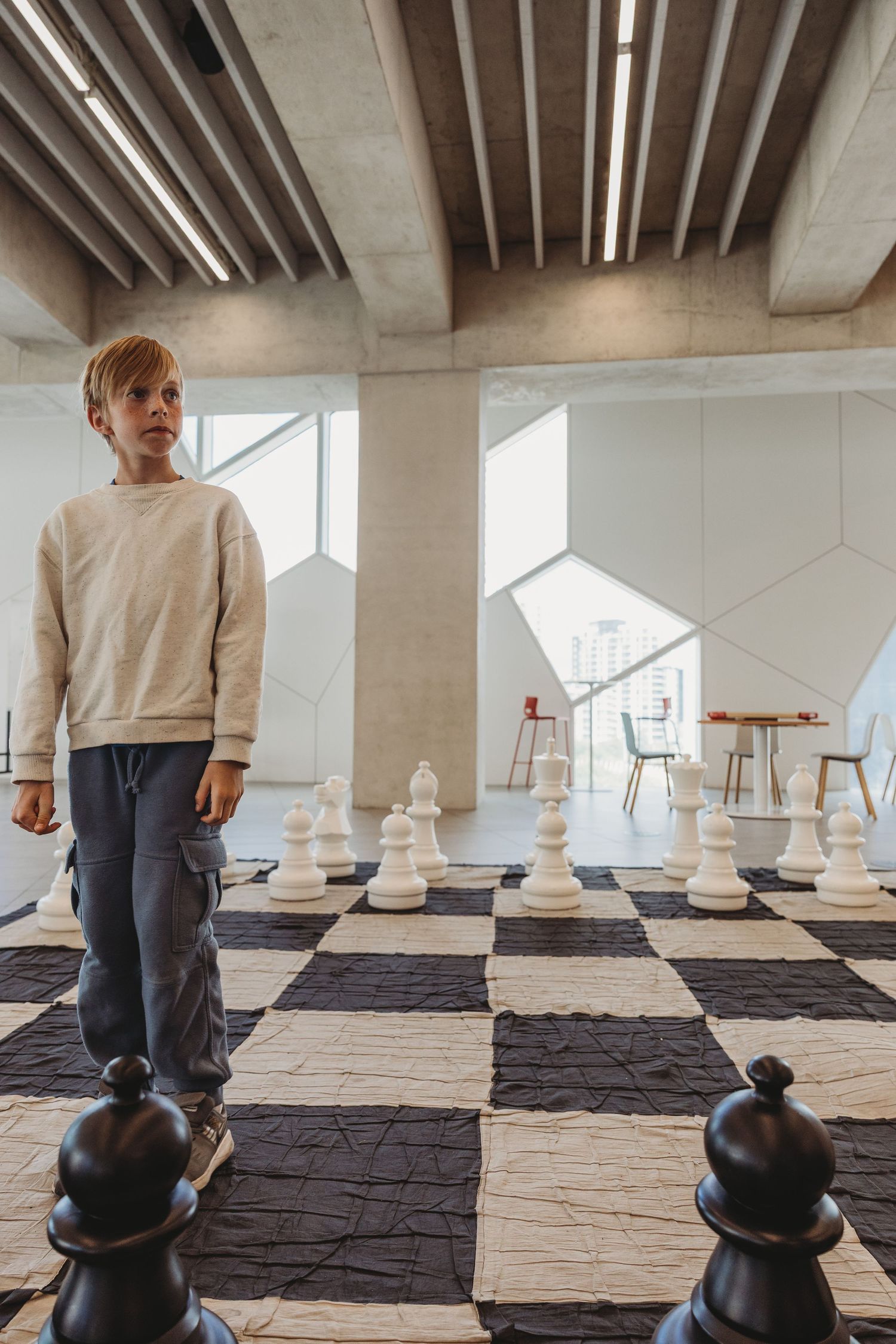 Boy playing giant chess in a Calgary family photography session at the Central Calgary Public Library.