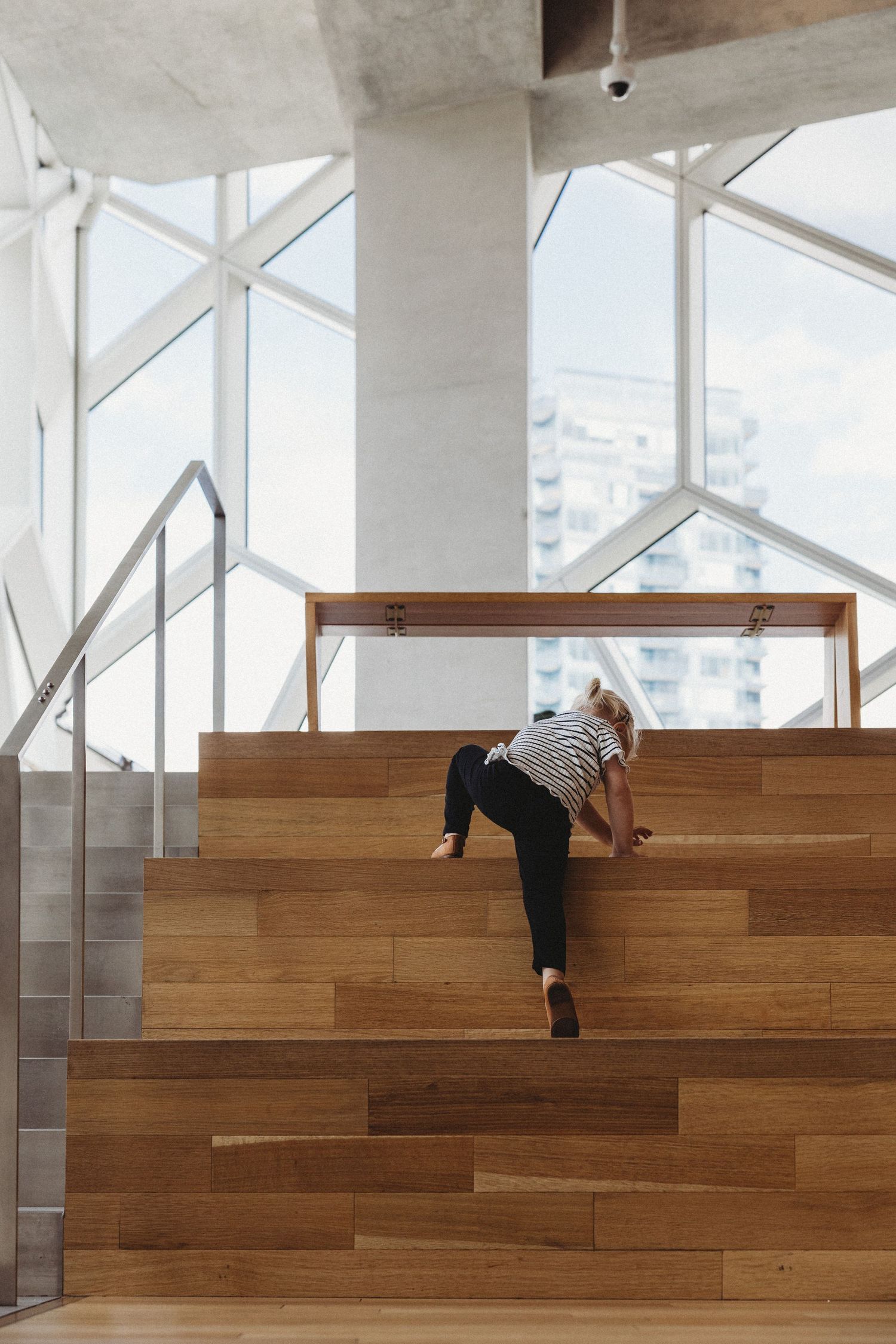 Toddler climbing stairs in a Calgary family photography session at the Central Calgary Public Library.