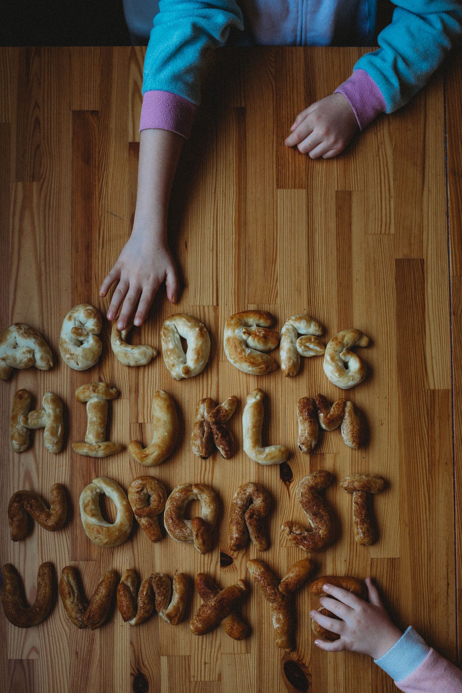 Girls reaching for food at the table in an in-home Calgary family photography session.