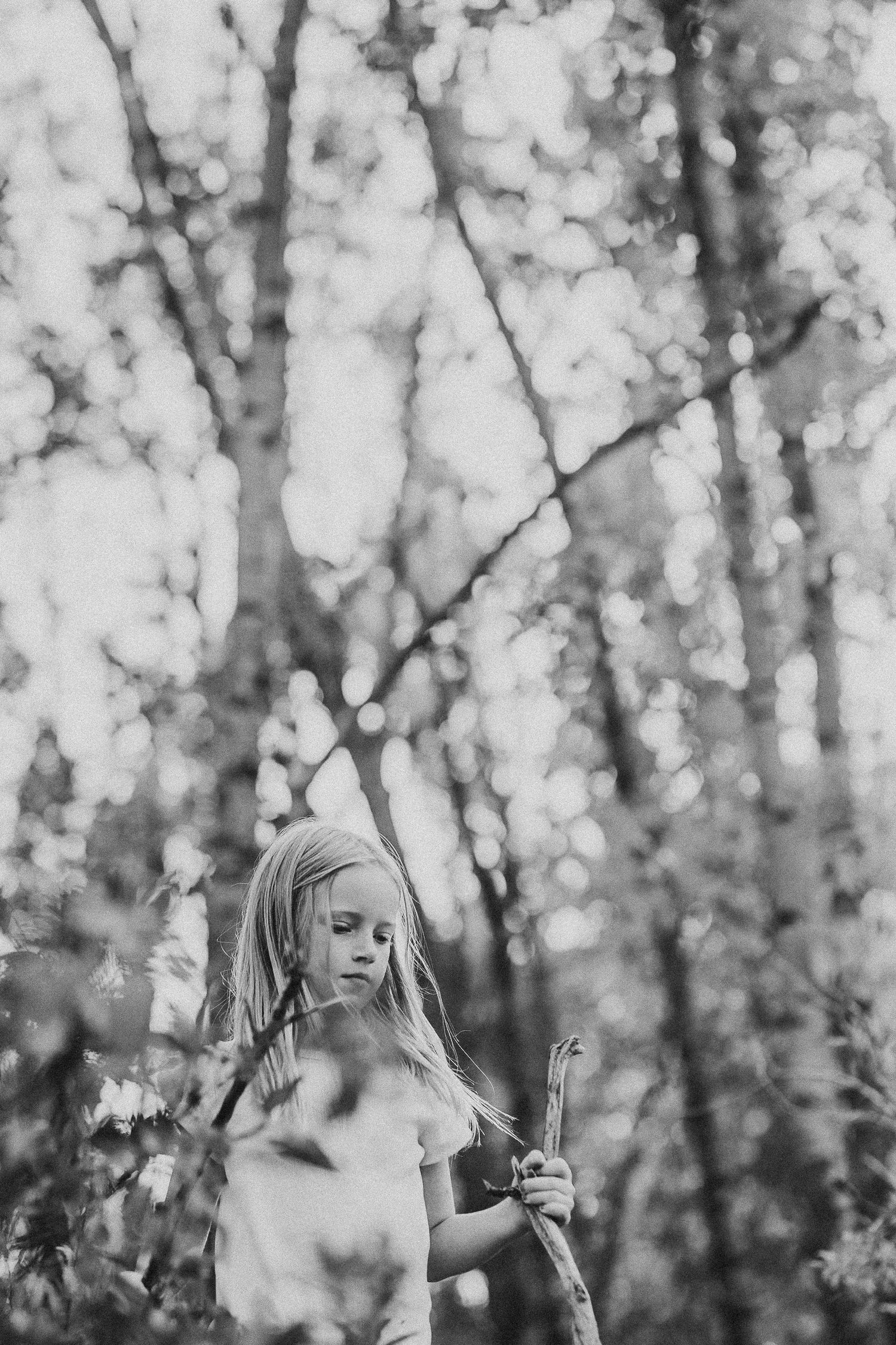 Girl walking through fall trees in a documentary style Calgary family photography session in Prince's Island Park