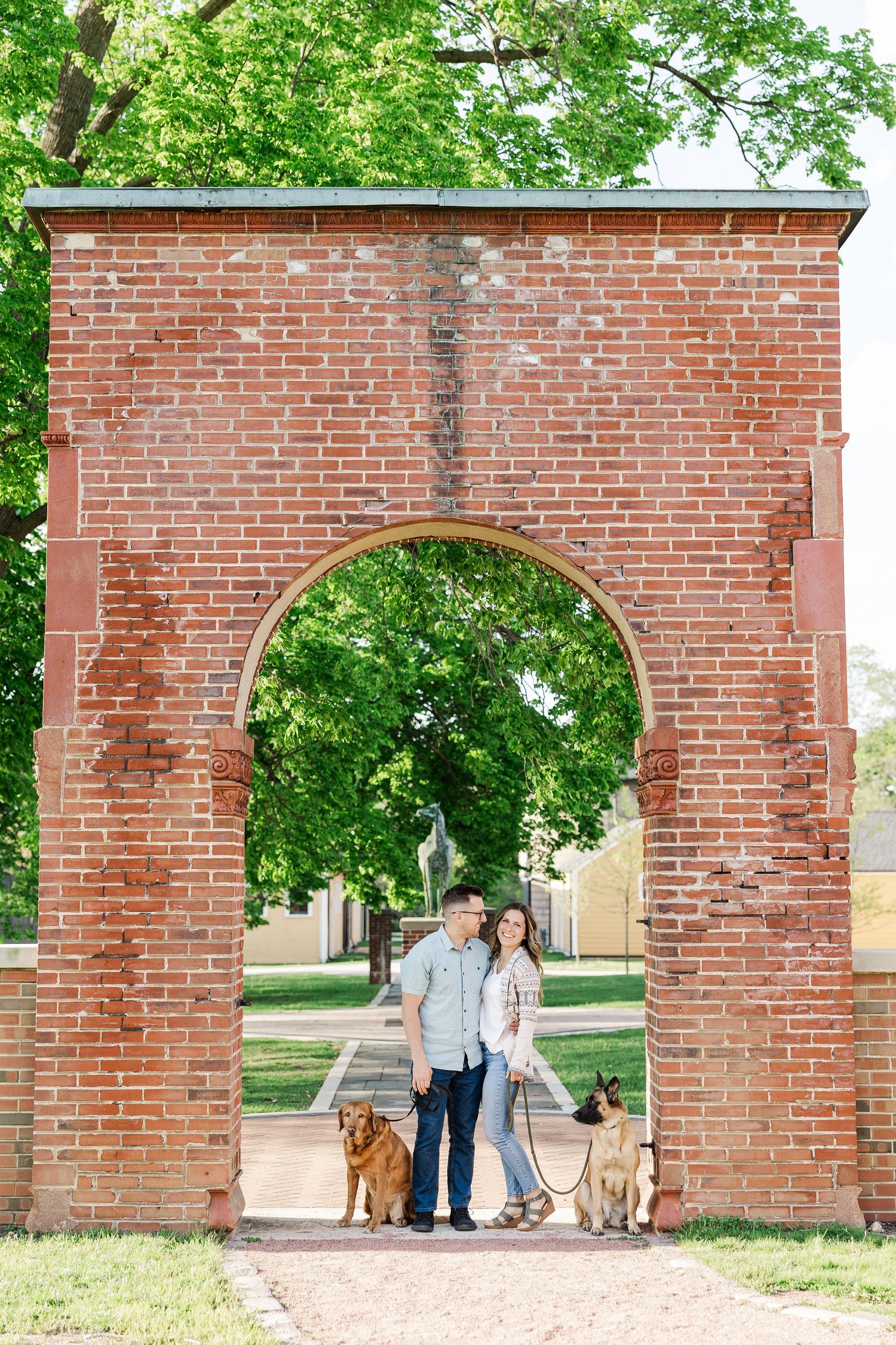 Engagement portraits with dogs under the brick arch at St. James Farm Preserve