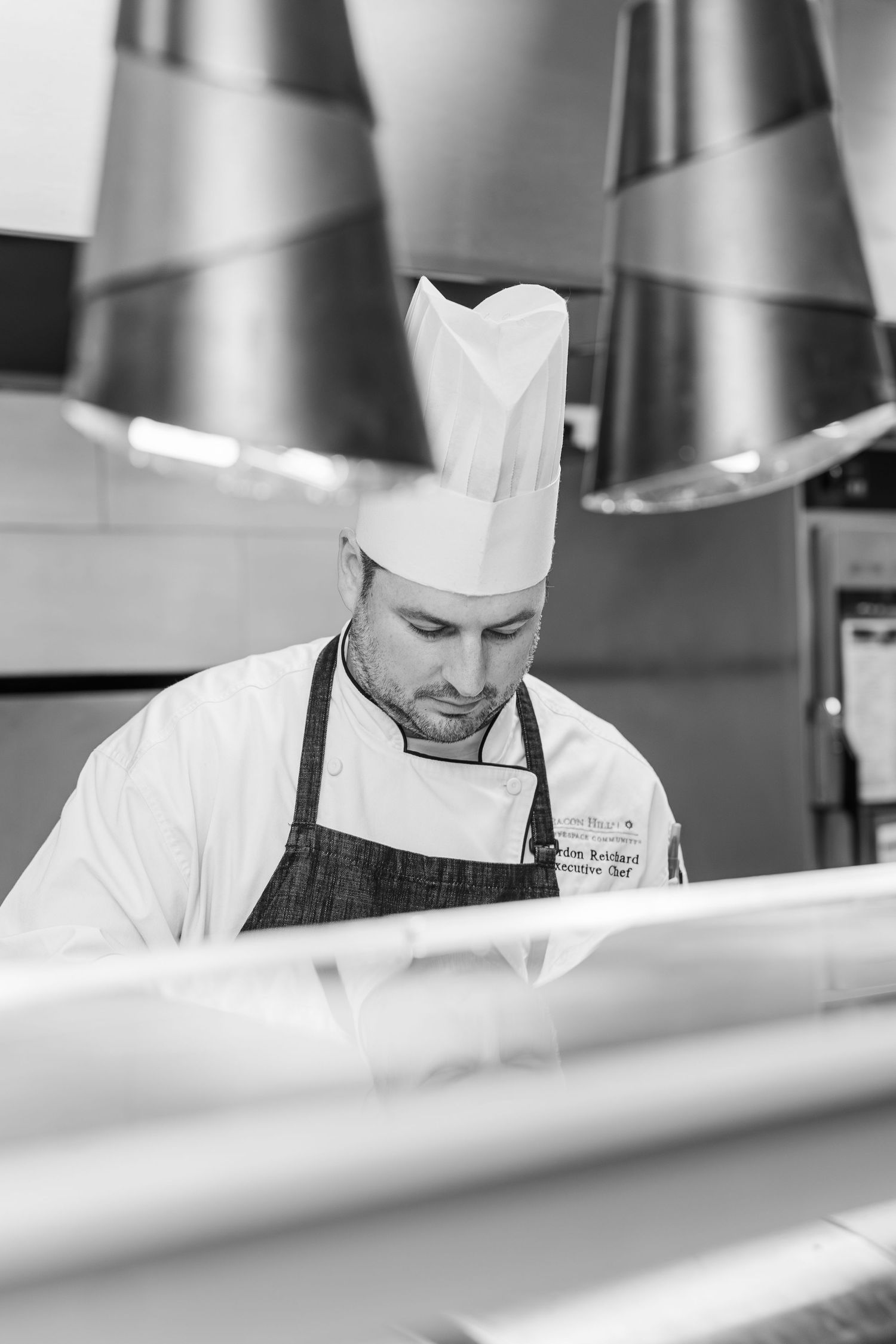 Black and white Beacon Hill senior living branding photo in Lombard, Illinois featuring chef plating food