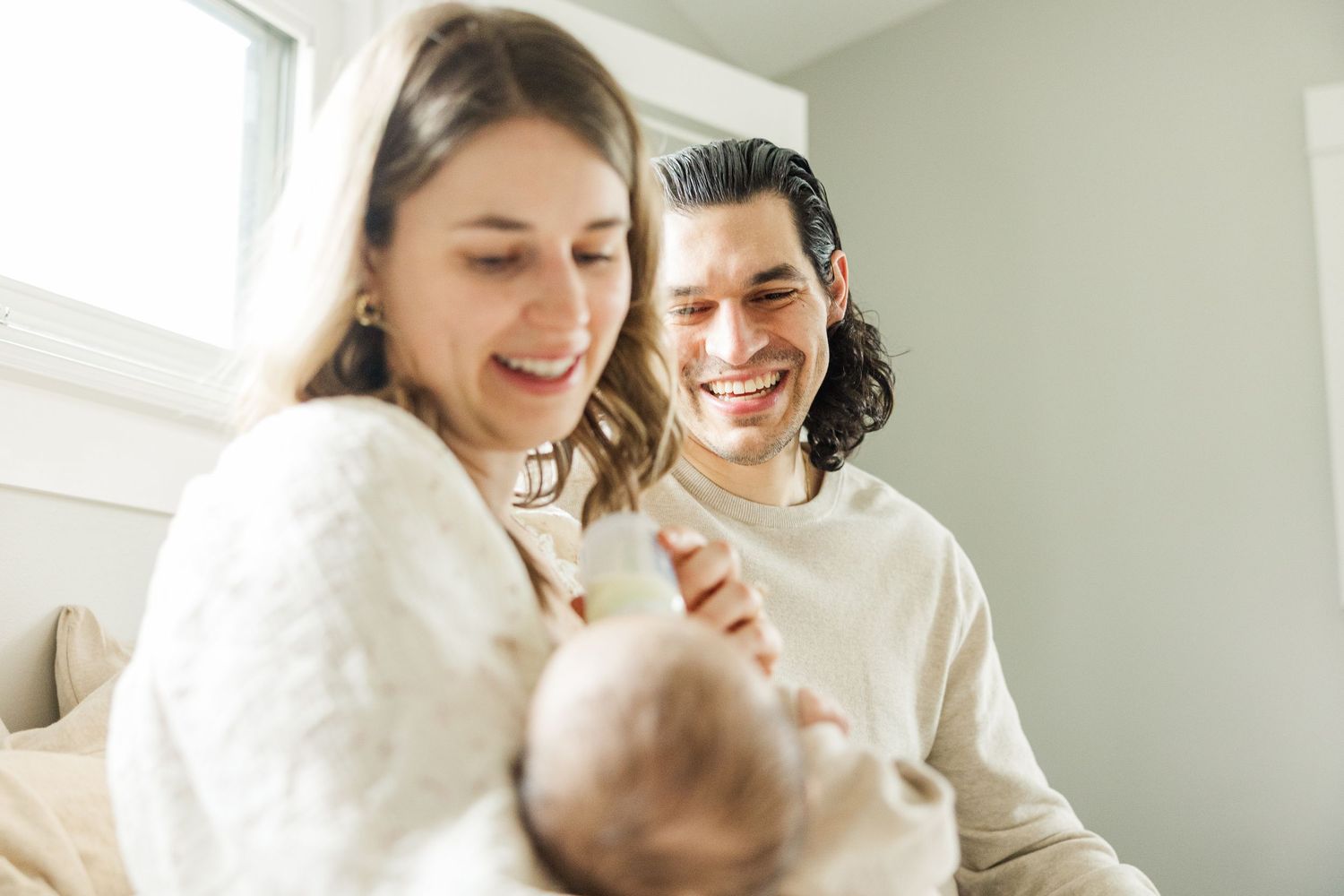 Mother feeding her newborn baby while father smiles during an in-home newborn photography session in Palatine IL