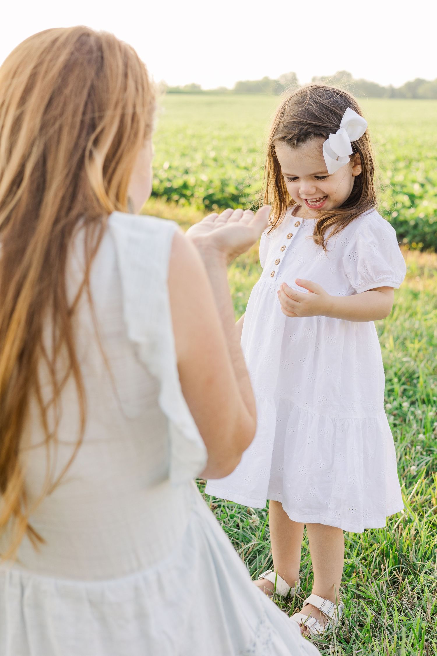 Two people in white dresses sharing a sweet moment in a sunny field.