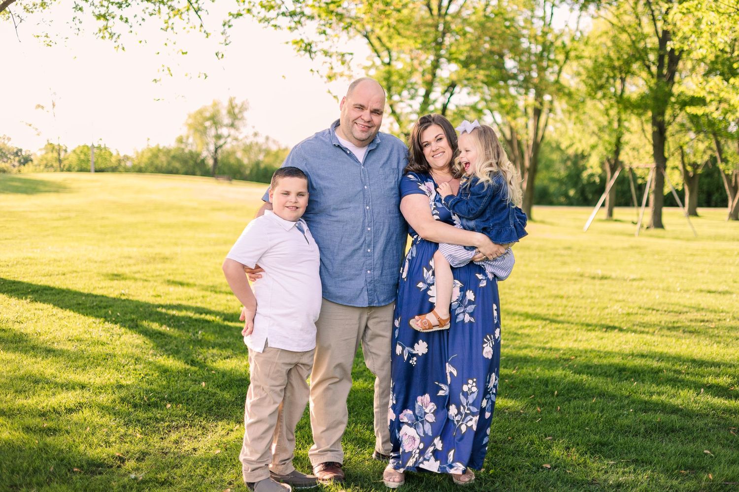 Family portrait outdoors in a green park during golden hour.