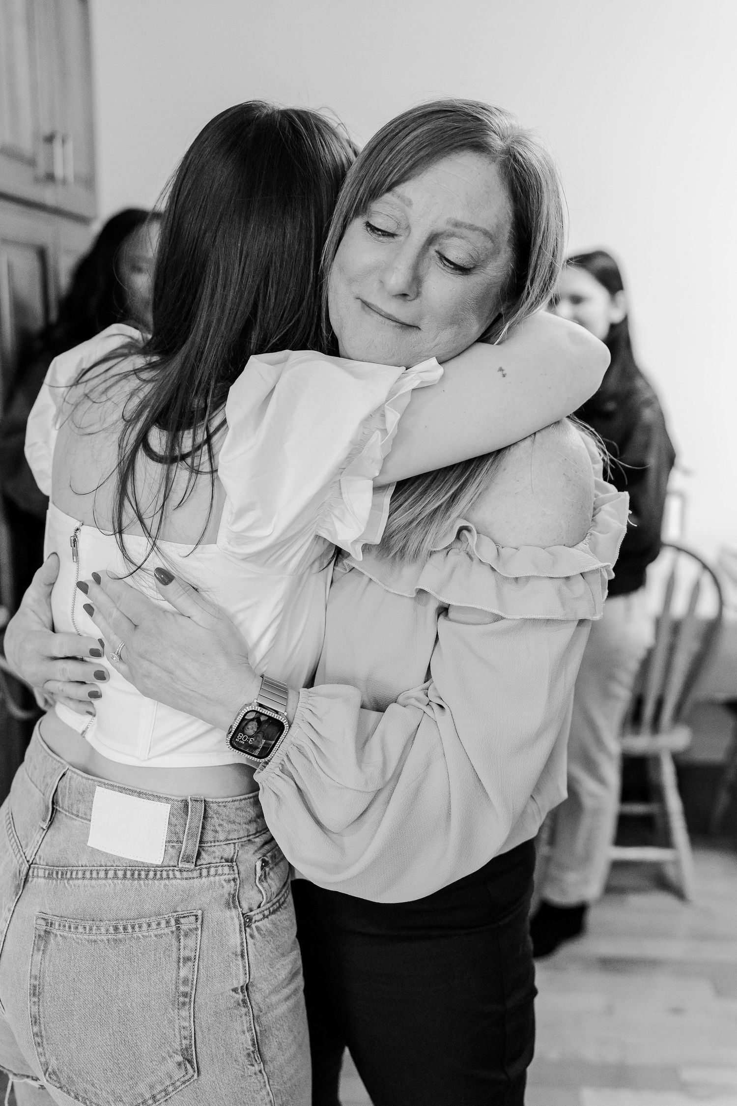 Black and white photo of two people embracing in casual attire.