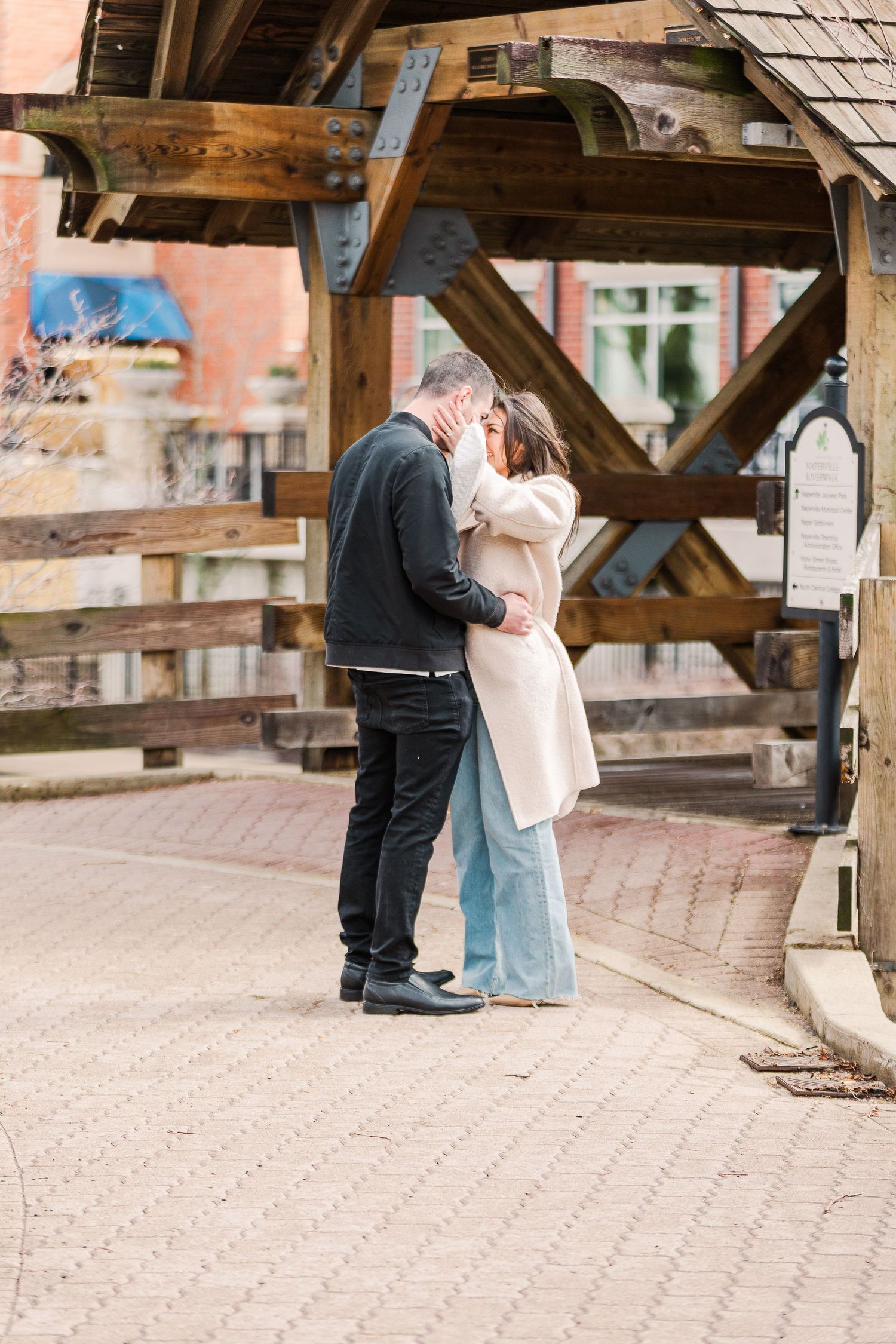 A tender moment captured between a couple sharing an intimate embrace on a brick pathway under wooden beams.