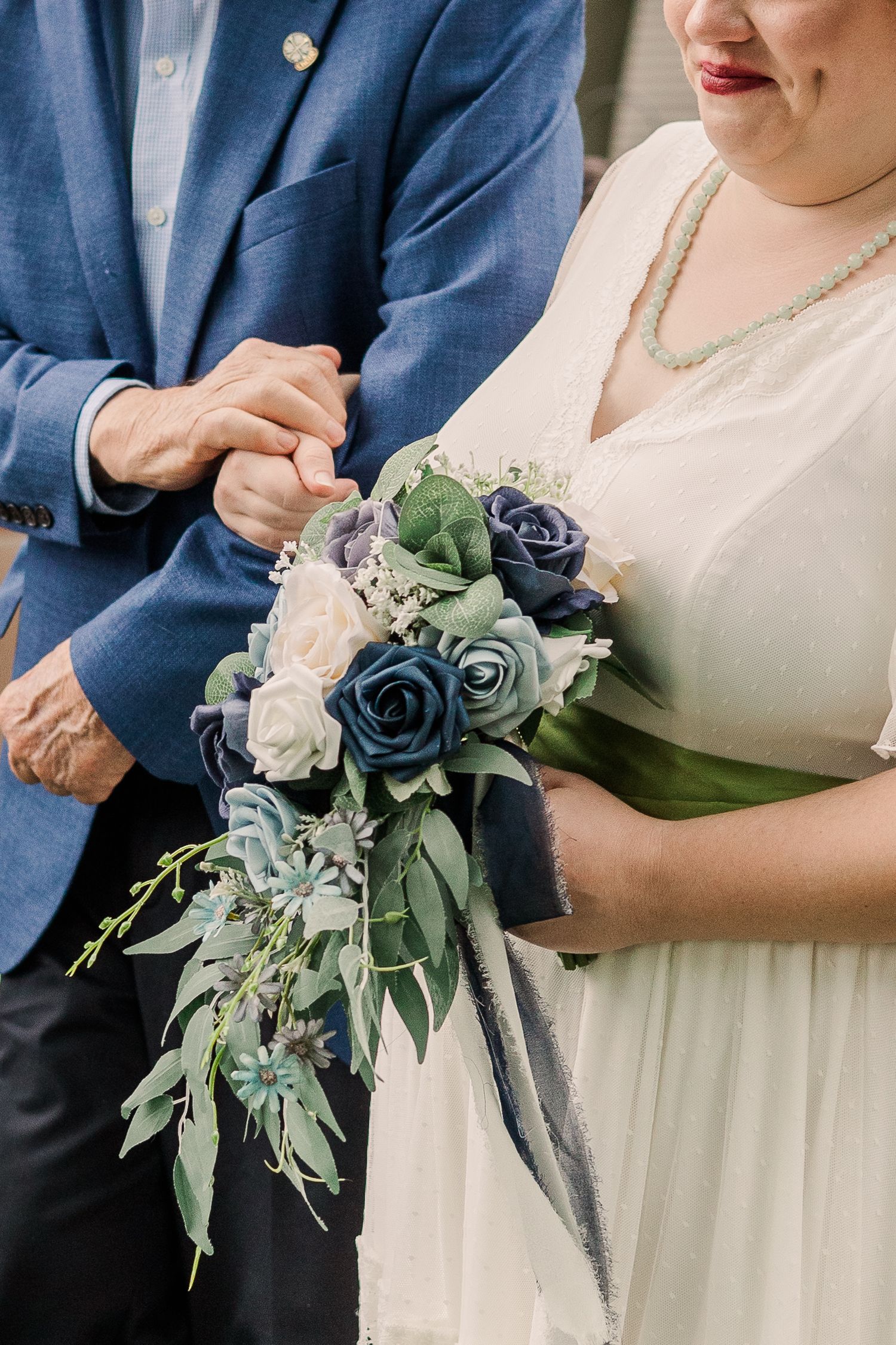Wedding bouquet featuring blue and white roses with cascading greenery and eucalyptus leaves.