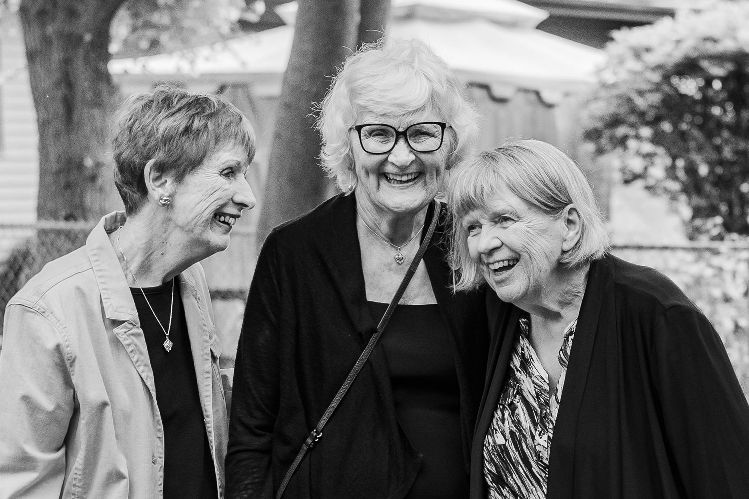 Three seniors share a candid laughing moment together in black and white.