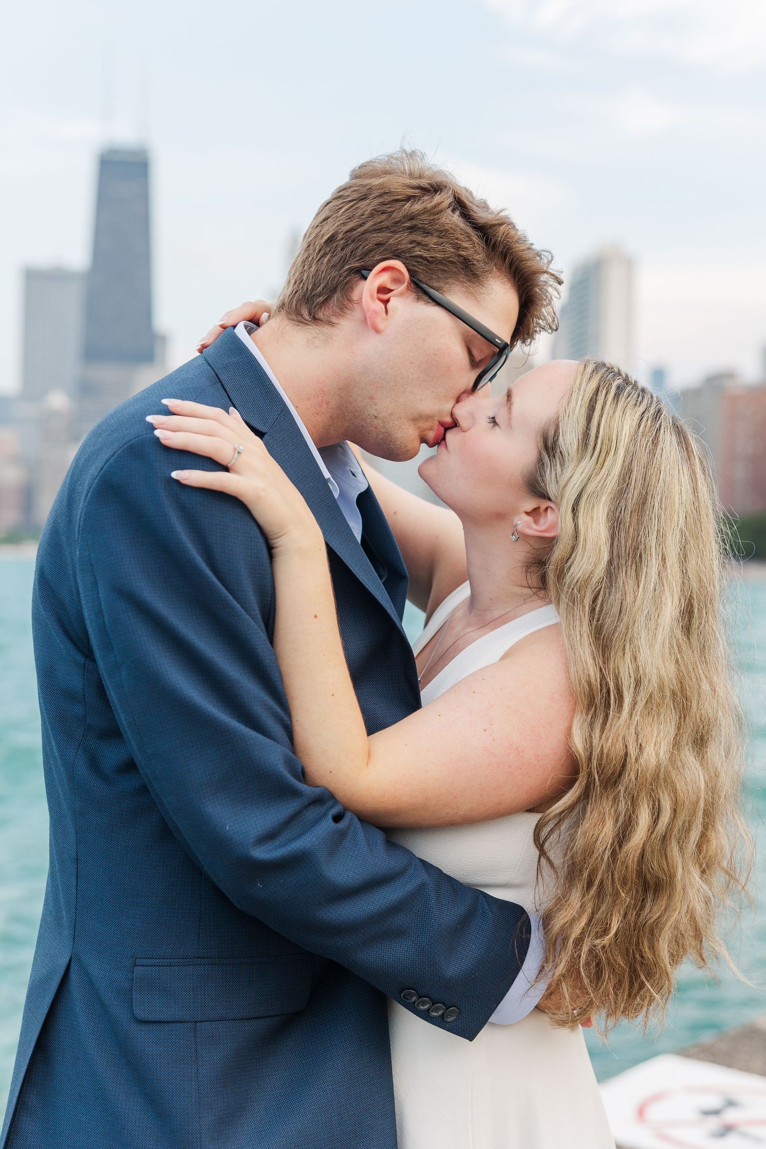 Elizabeth and Joe kissing with the Chicago skyline in the background at North Avenue Beach during sunset