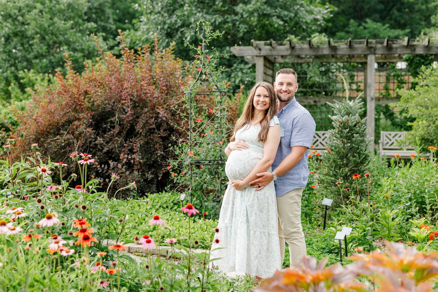 Expecting parents smiling together among colorful flowers during a maternity session