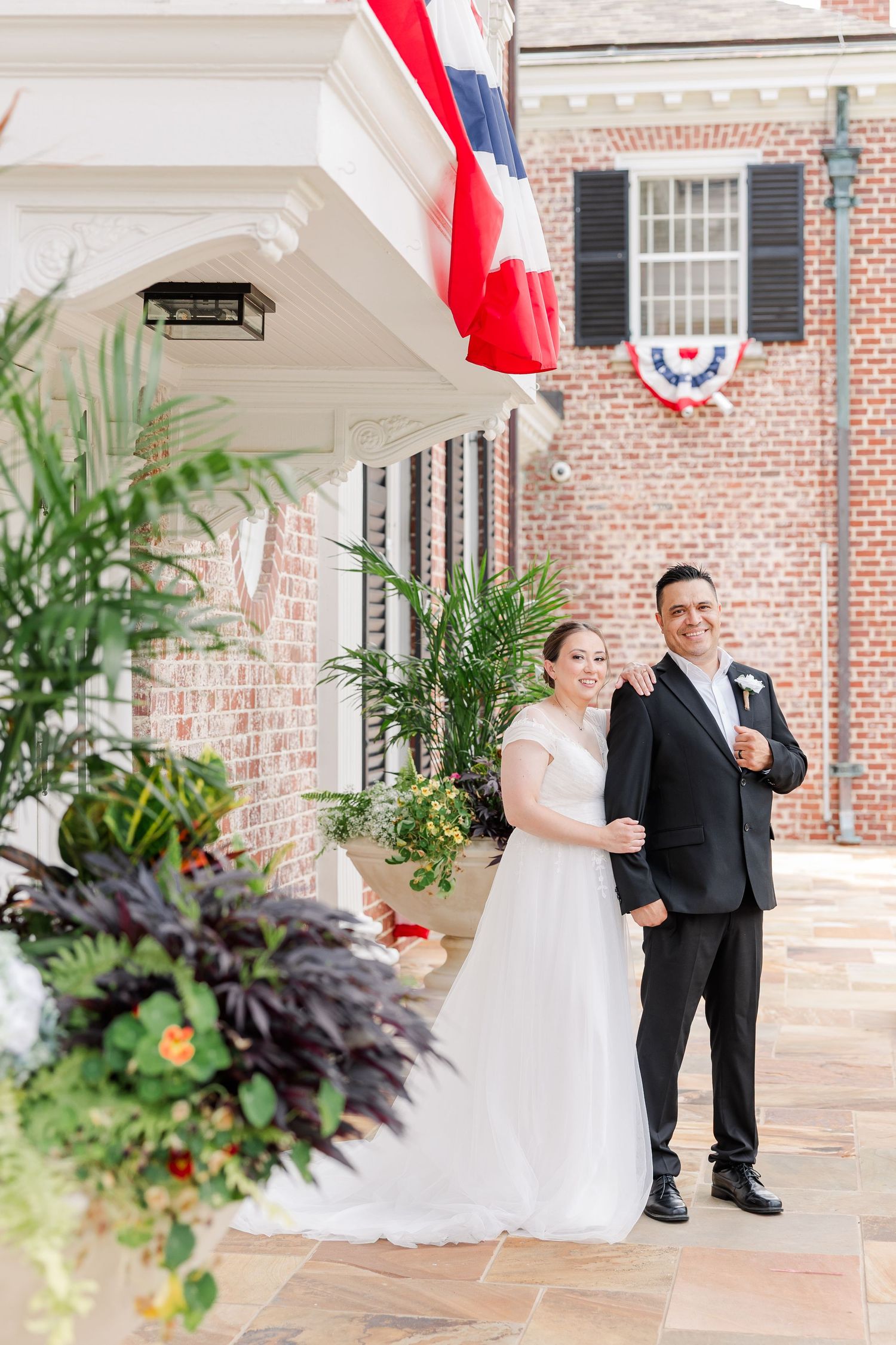Bride and groom standing together beneath the columned entrance of McCormick House at Cantigny Park.