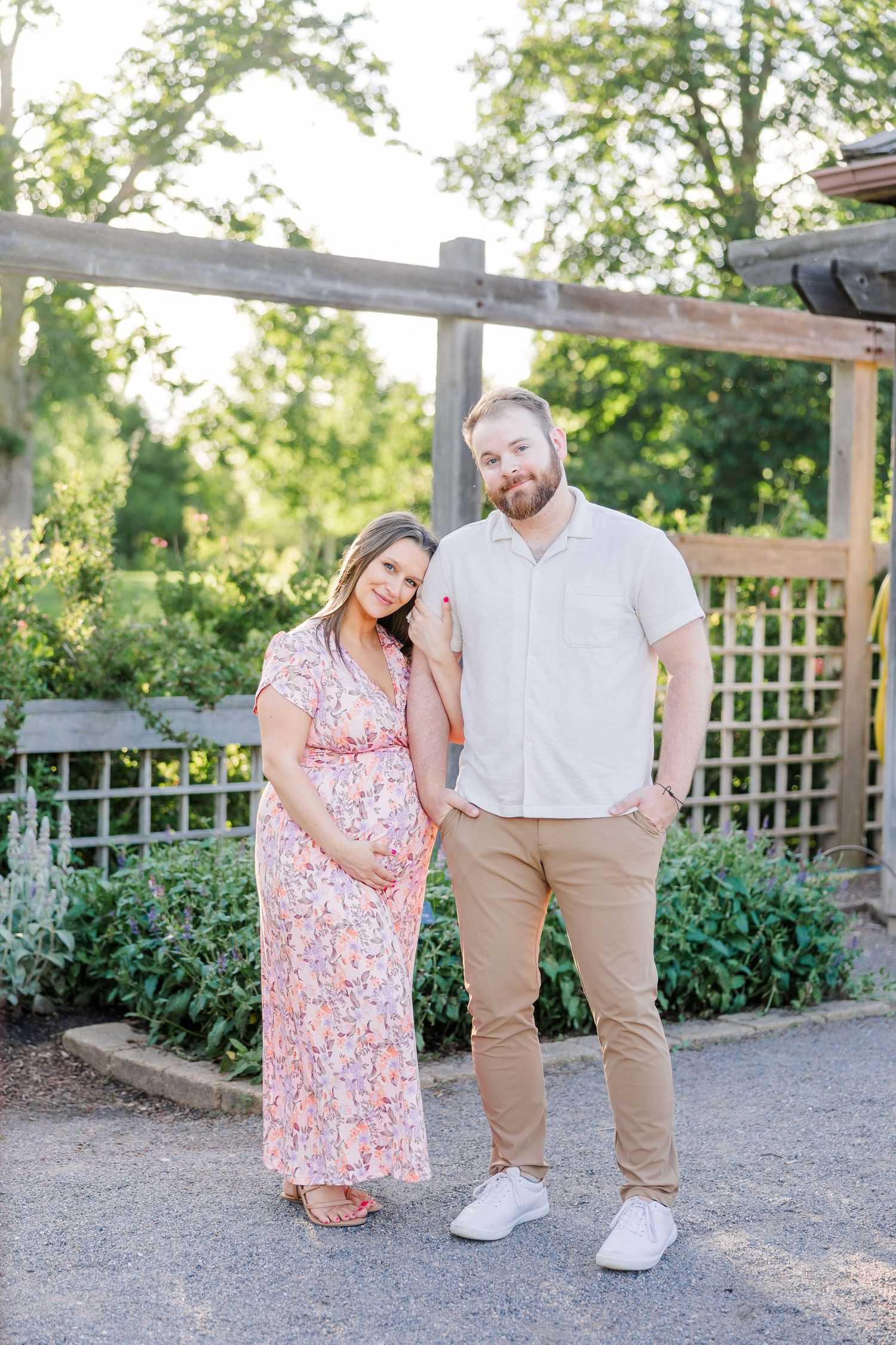 Couple standing together under a garden trellis during their Cantigny maternity photos in Wheaton Illinois