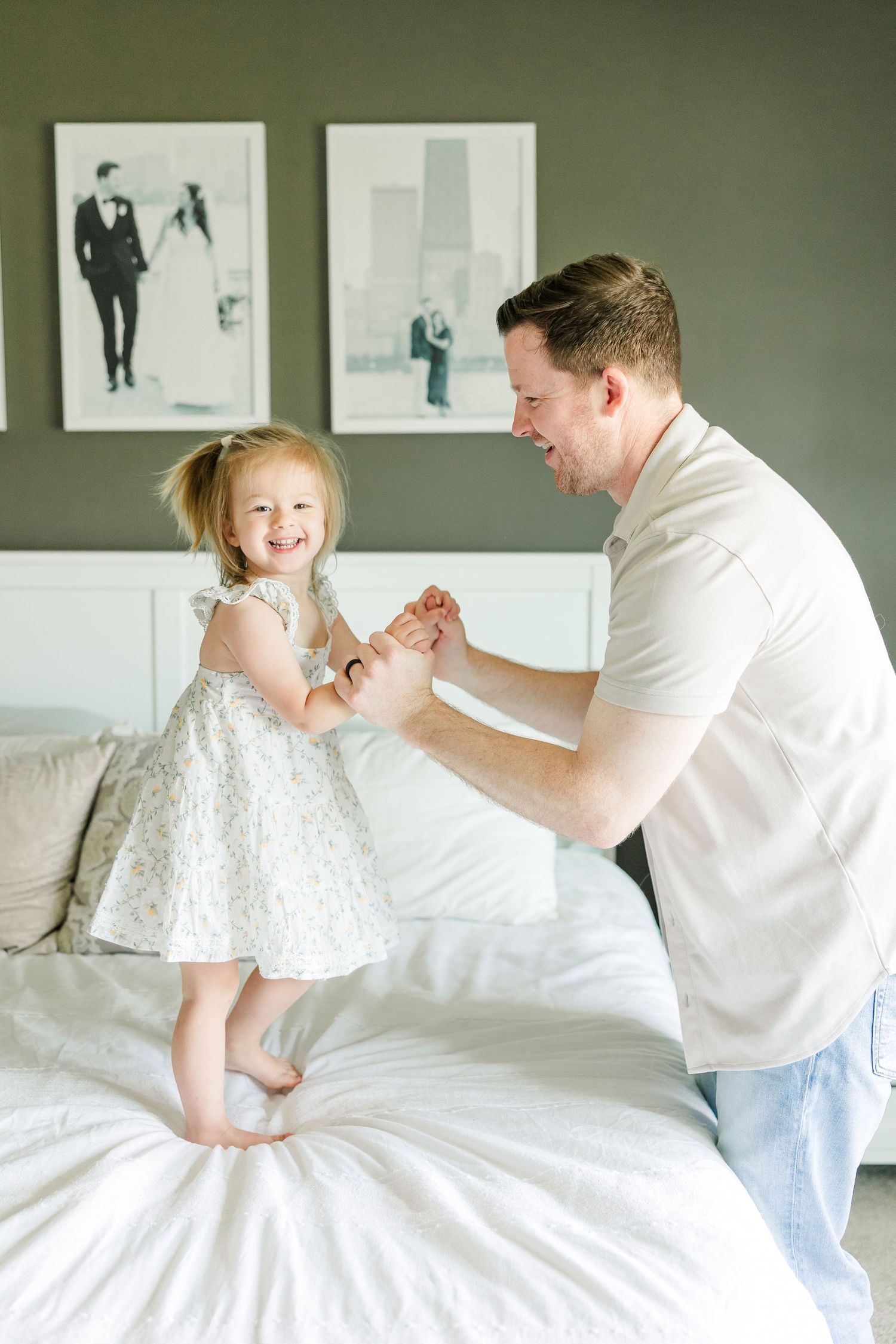 Dad playing with big sister on the bed during a relaxed in-home newborn session in Huntley IL