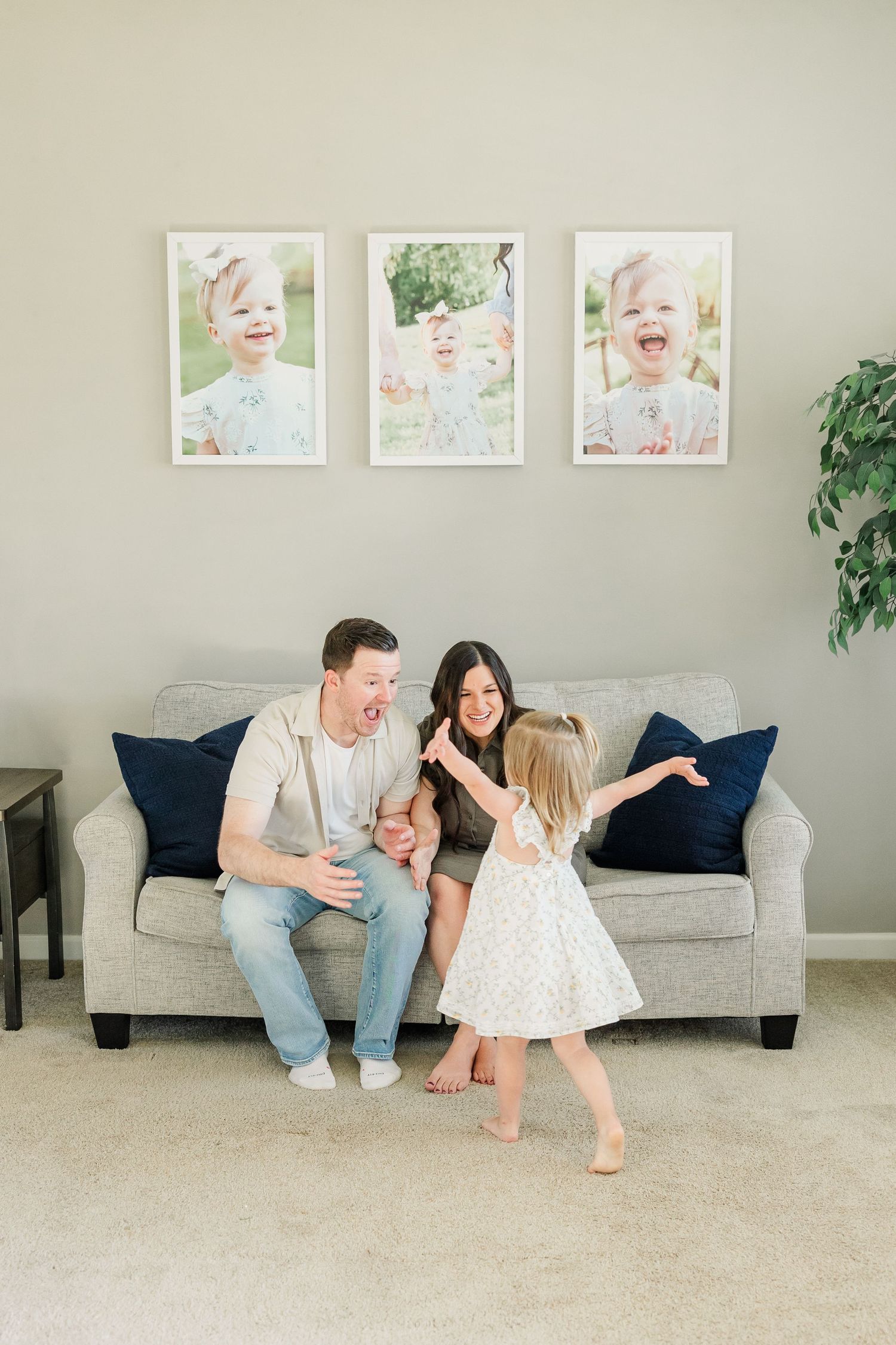 Huntley IL in-home newborn session with parents sitting together while big sister stands in front of the couch