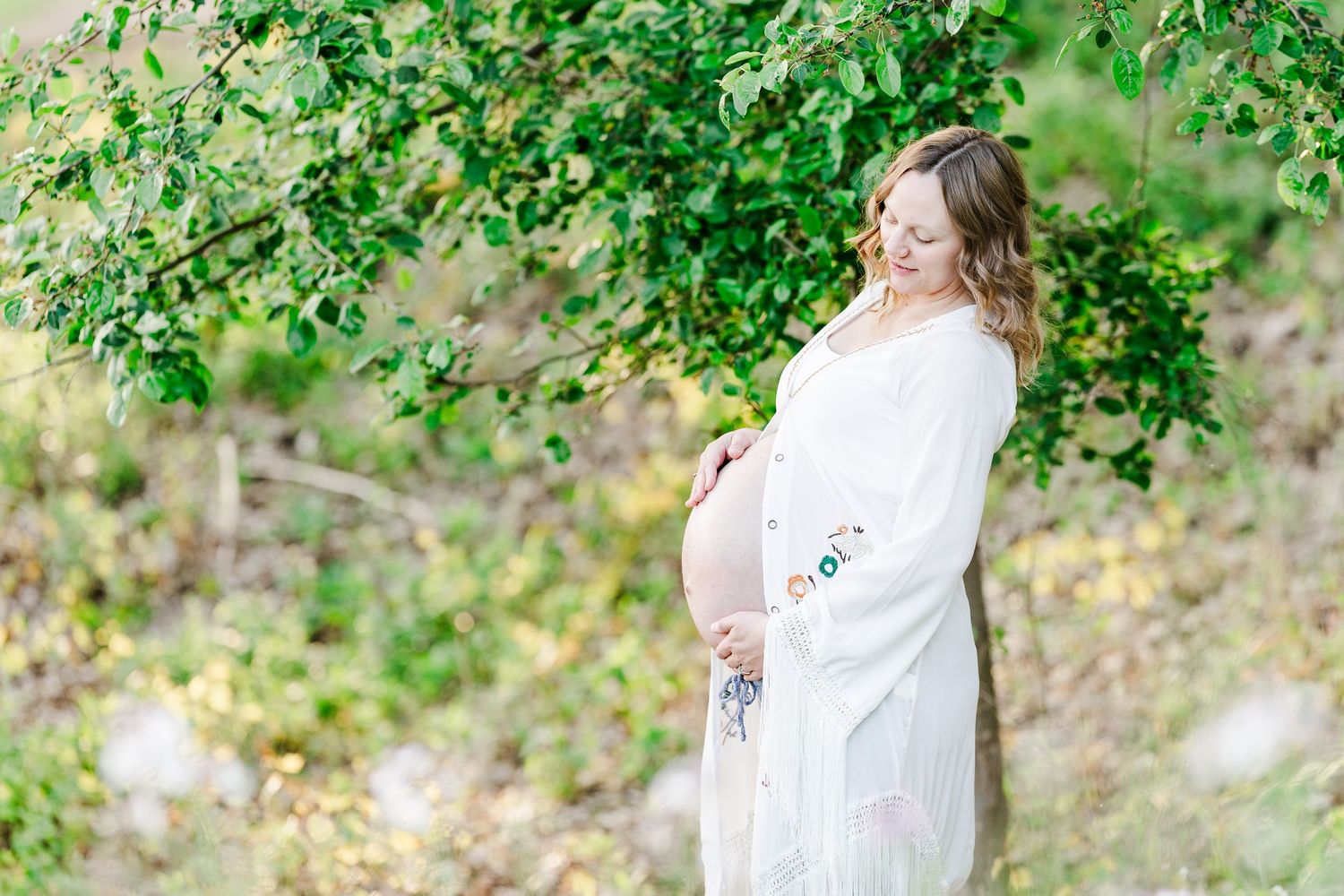 Mother standing in spring greenery during a maternity session at Veterans Acres Nature Preserve.