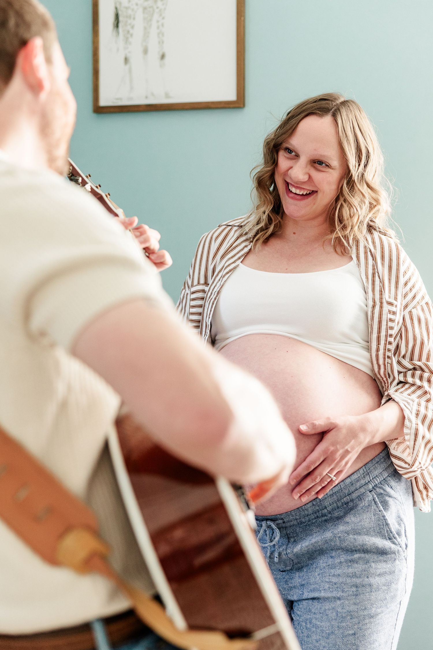 Music-inspired maternity photo with father playing guitar for mother and babies during an in-home session in Crystal Lake.