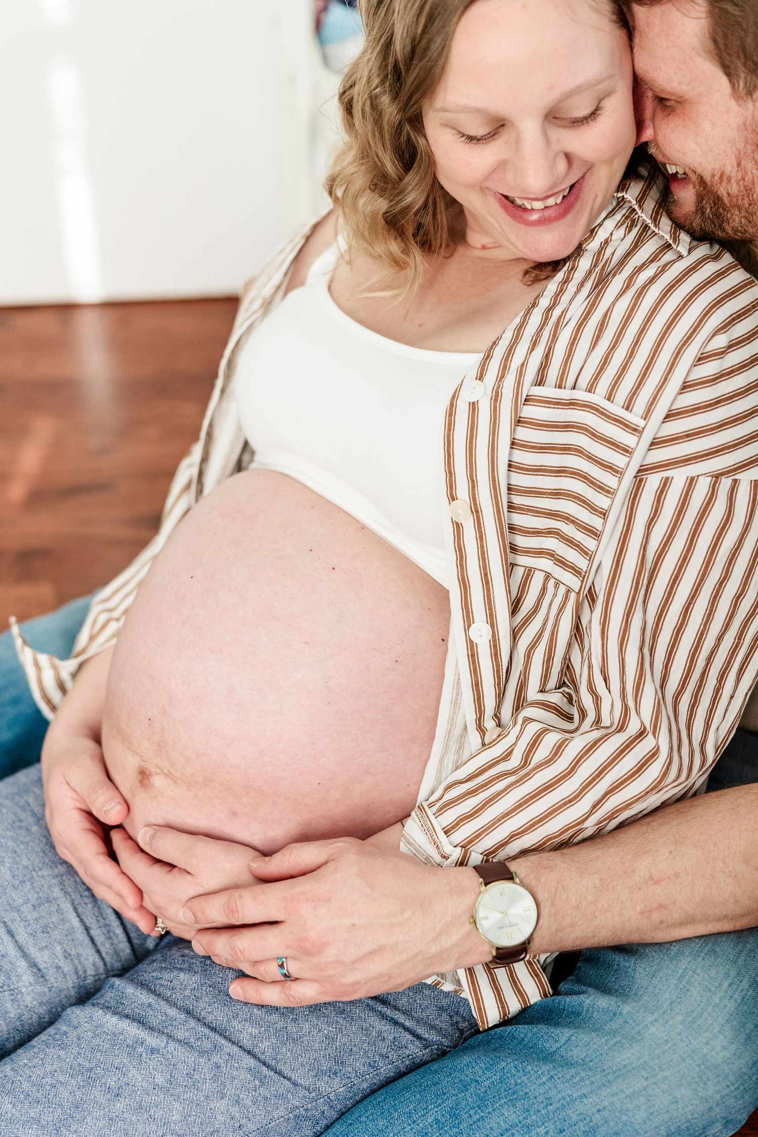 Close-up maternity portrait of mother holding baby bump during an in-home session in Crystal Lake.