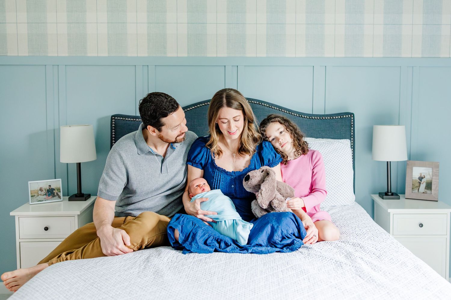 Family sitting on bed during bright in-home lifestyle newborn session in Crystal Lake, Illinois