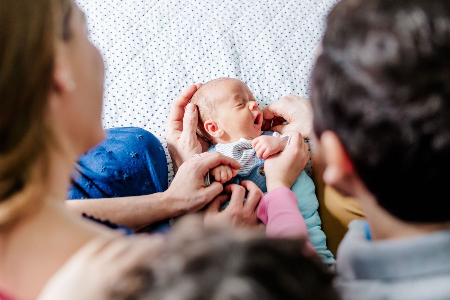 Parents and big sister looking at newborn during lifestyle newborn session in Crystal Lake, Illinois