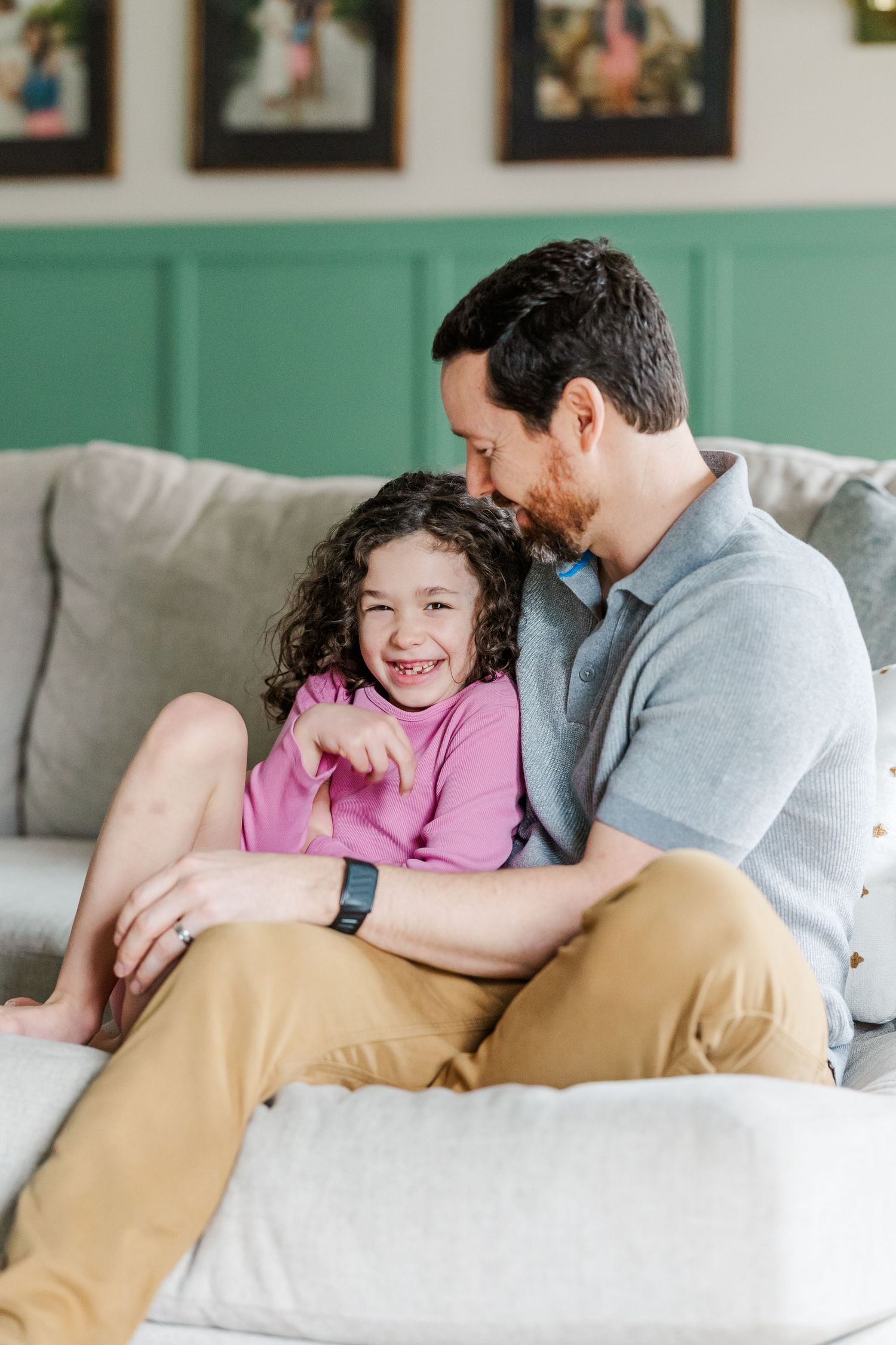 Father cuddles daughter on couch during in-home lifestyle newborn session in Crystal Lake, Illinois