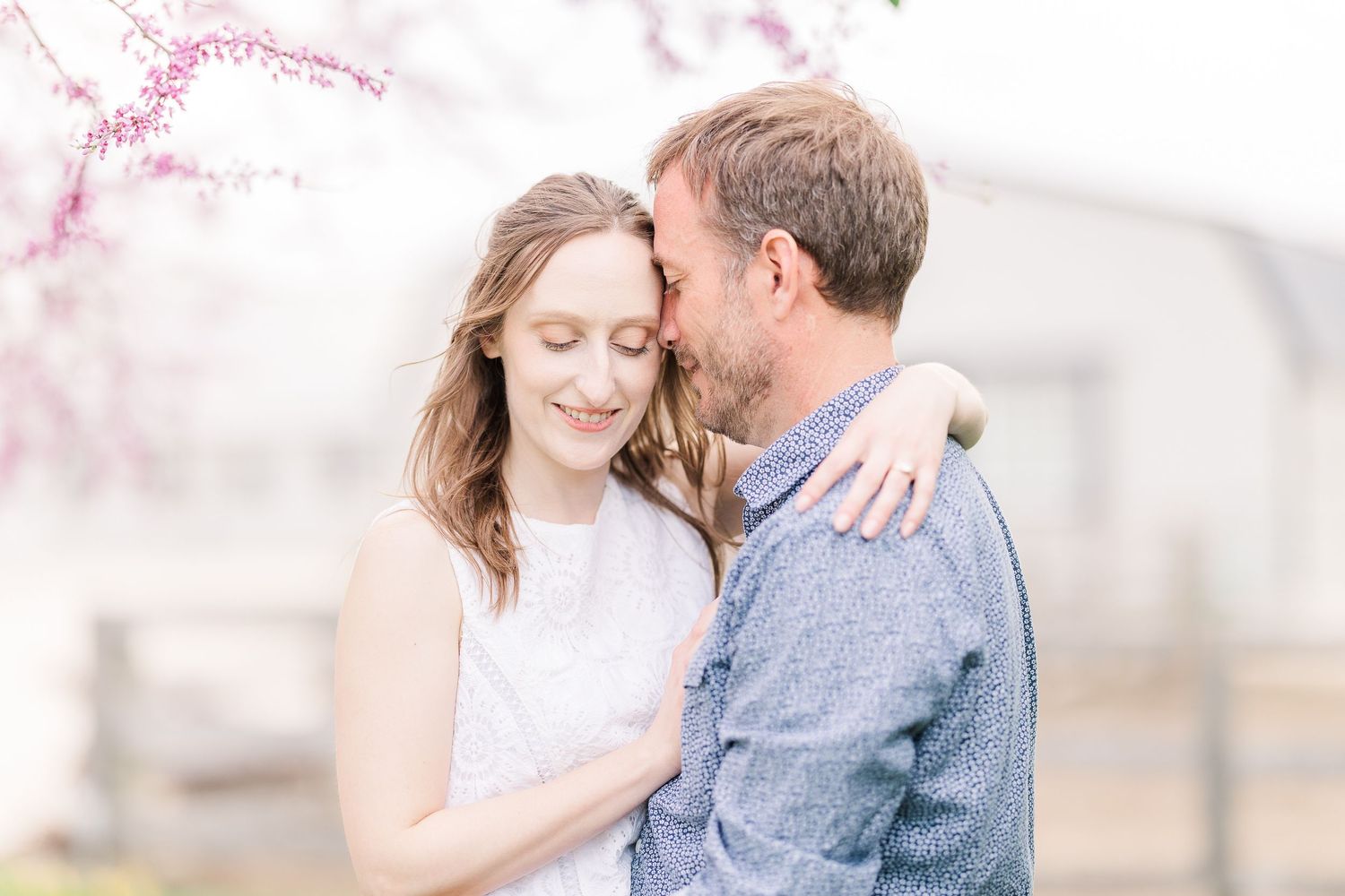 A romantic embrace under soft spring light and cherry blossoms.