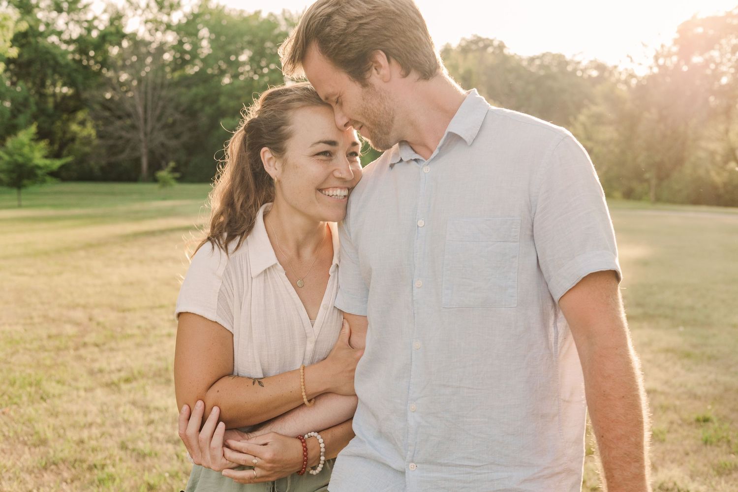 Couple sharing an intimate moment while laughing together in golden sunlight.