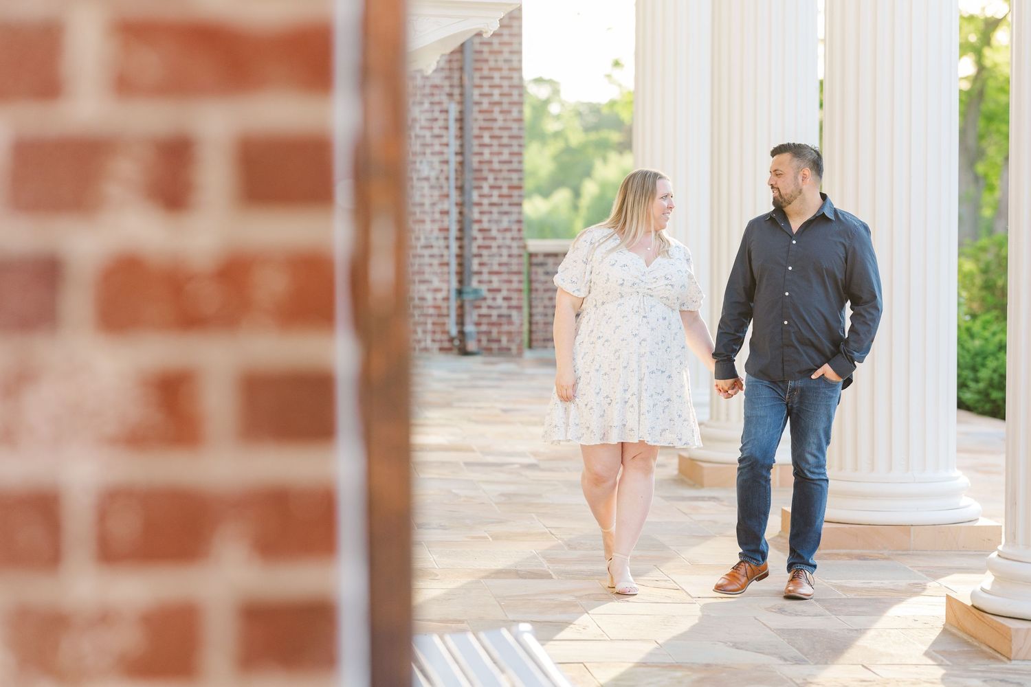 Casual portrait between white columns on a covered porch.