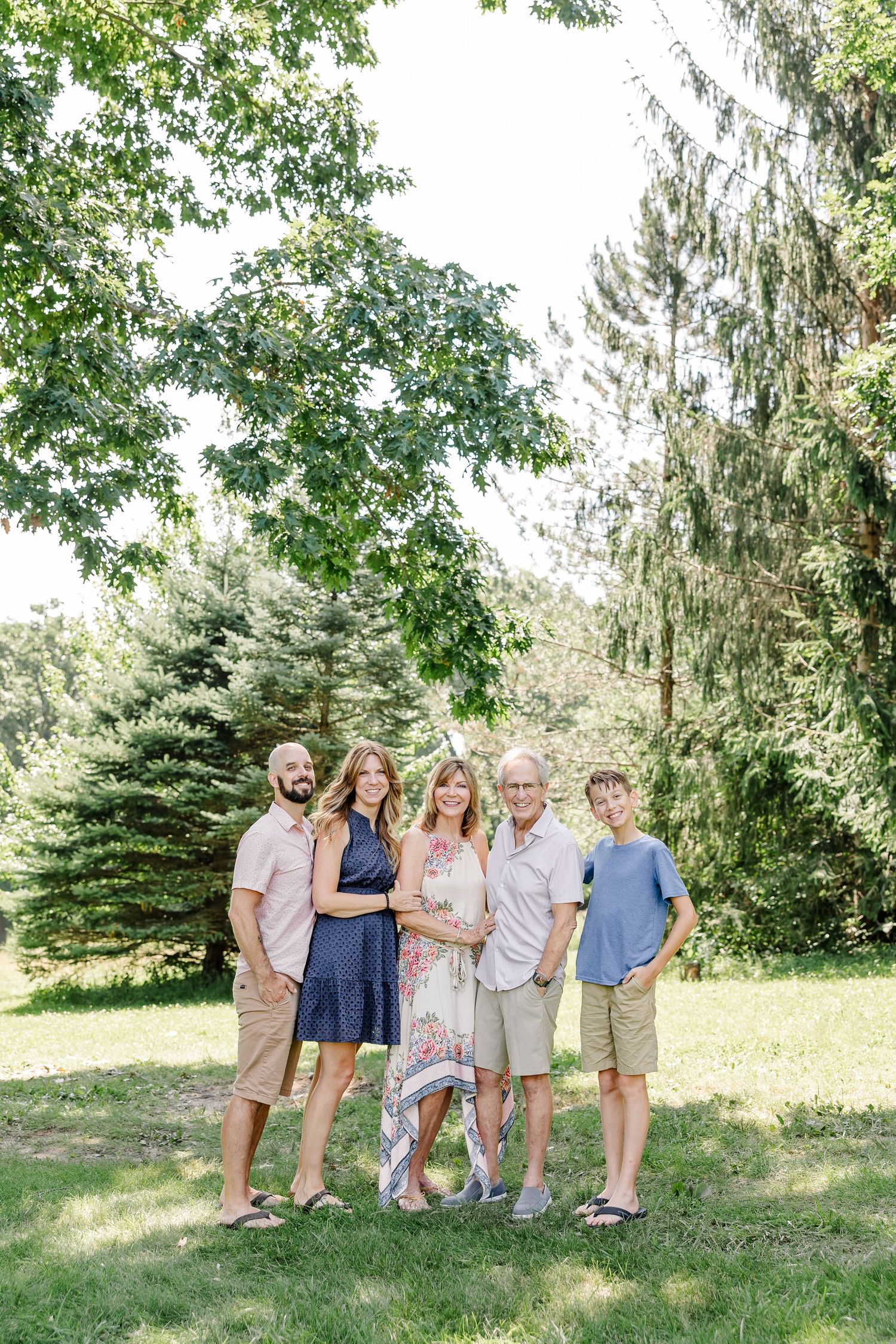 Family standing together under the trees during a summer portrait session in Crystal Lake, Illinois.