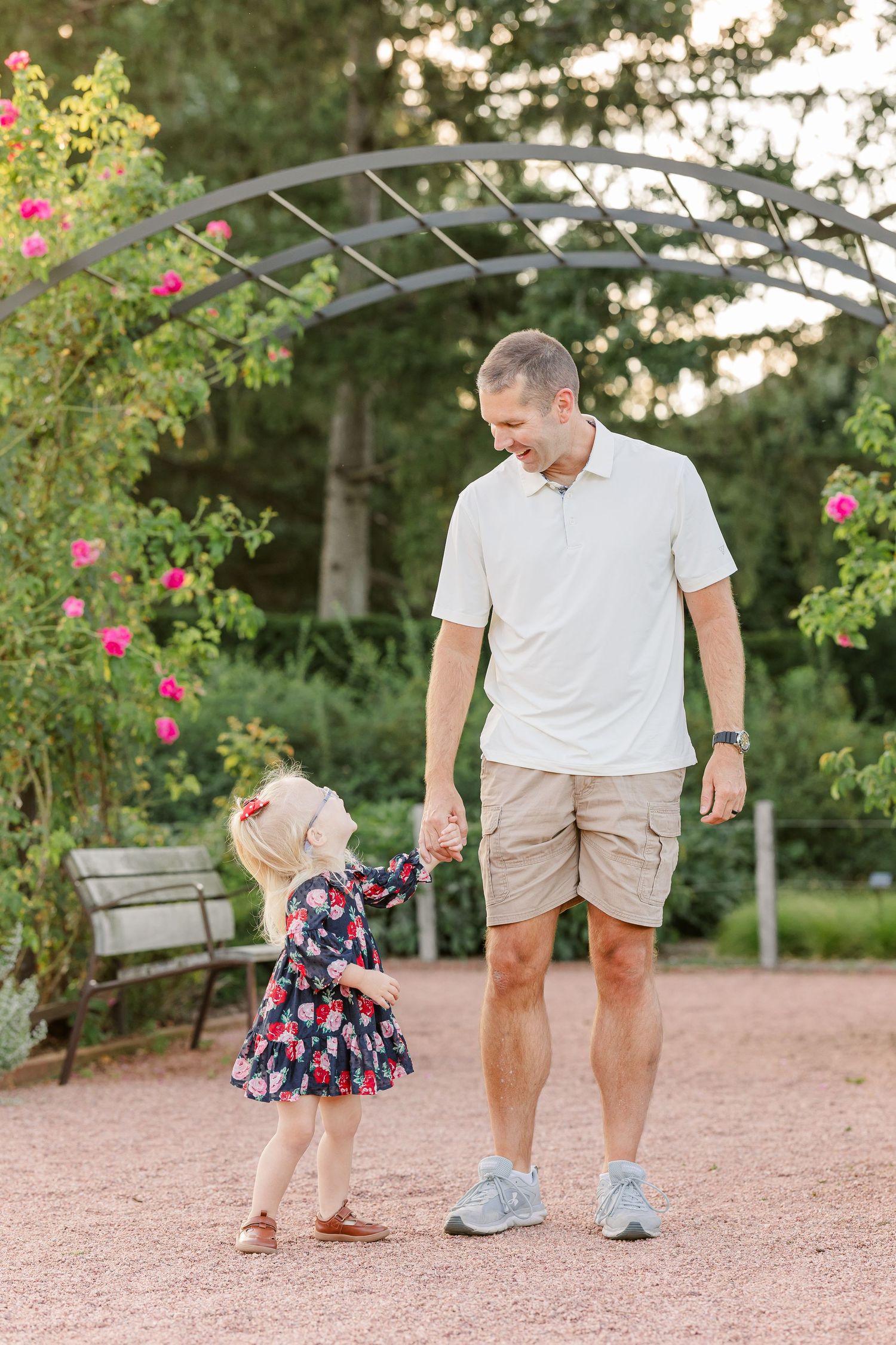 Andrew walking hand in hand with Caroline beneath a flower-covered arch at Cantigny Park.