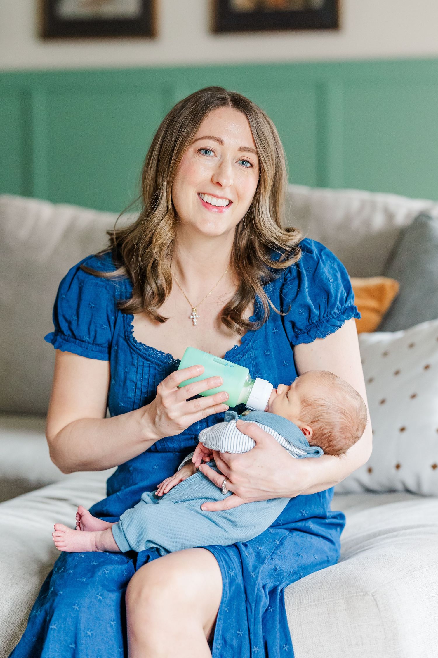 Mother holding newborn son on couch during in-home lifestyle newborn session in Crystal Lake, Illinois