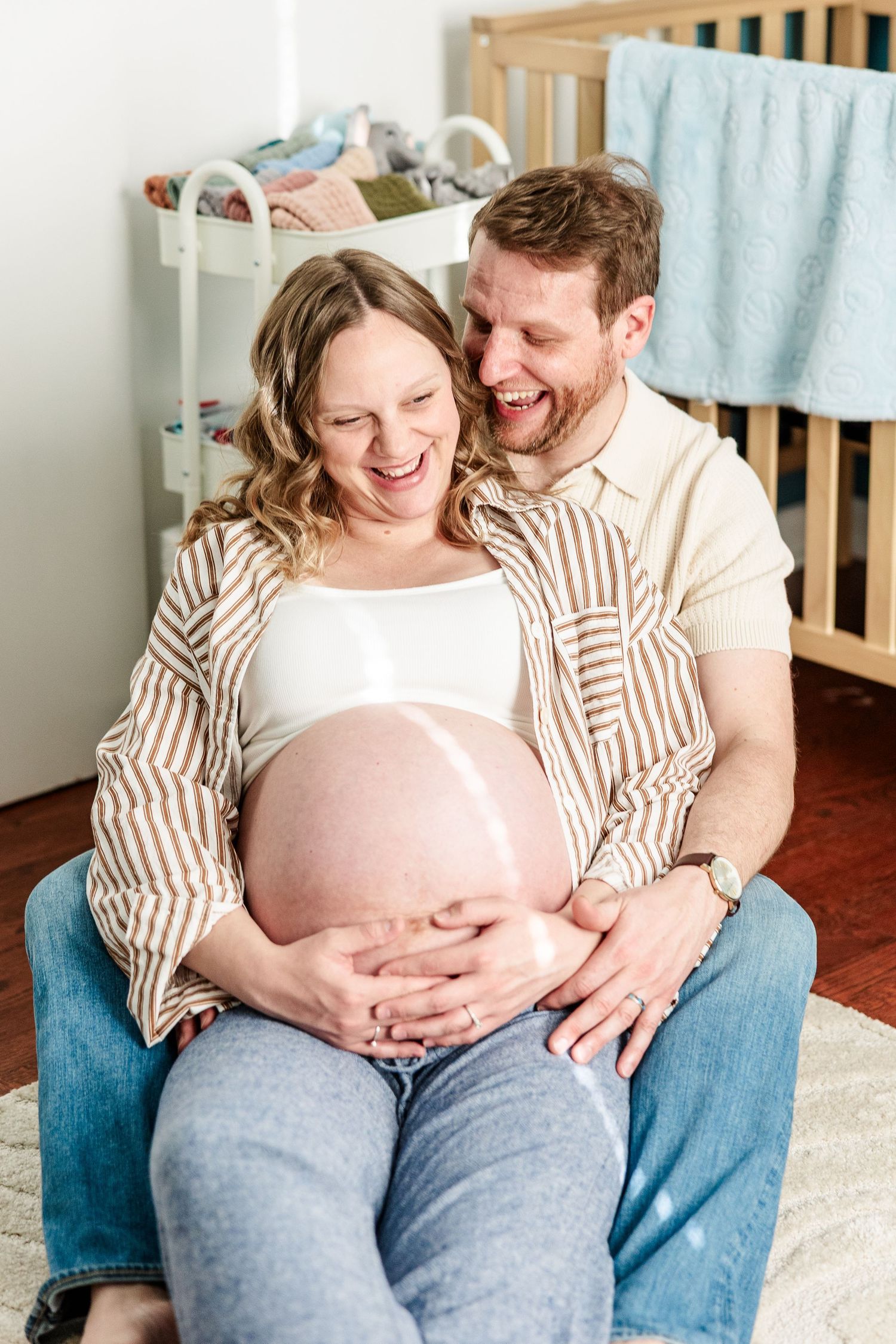 Expecting parents sitting together in twin boys’ nursery during an in-home maternity session in Crystal Lake.
