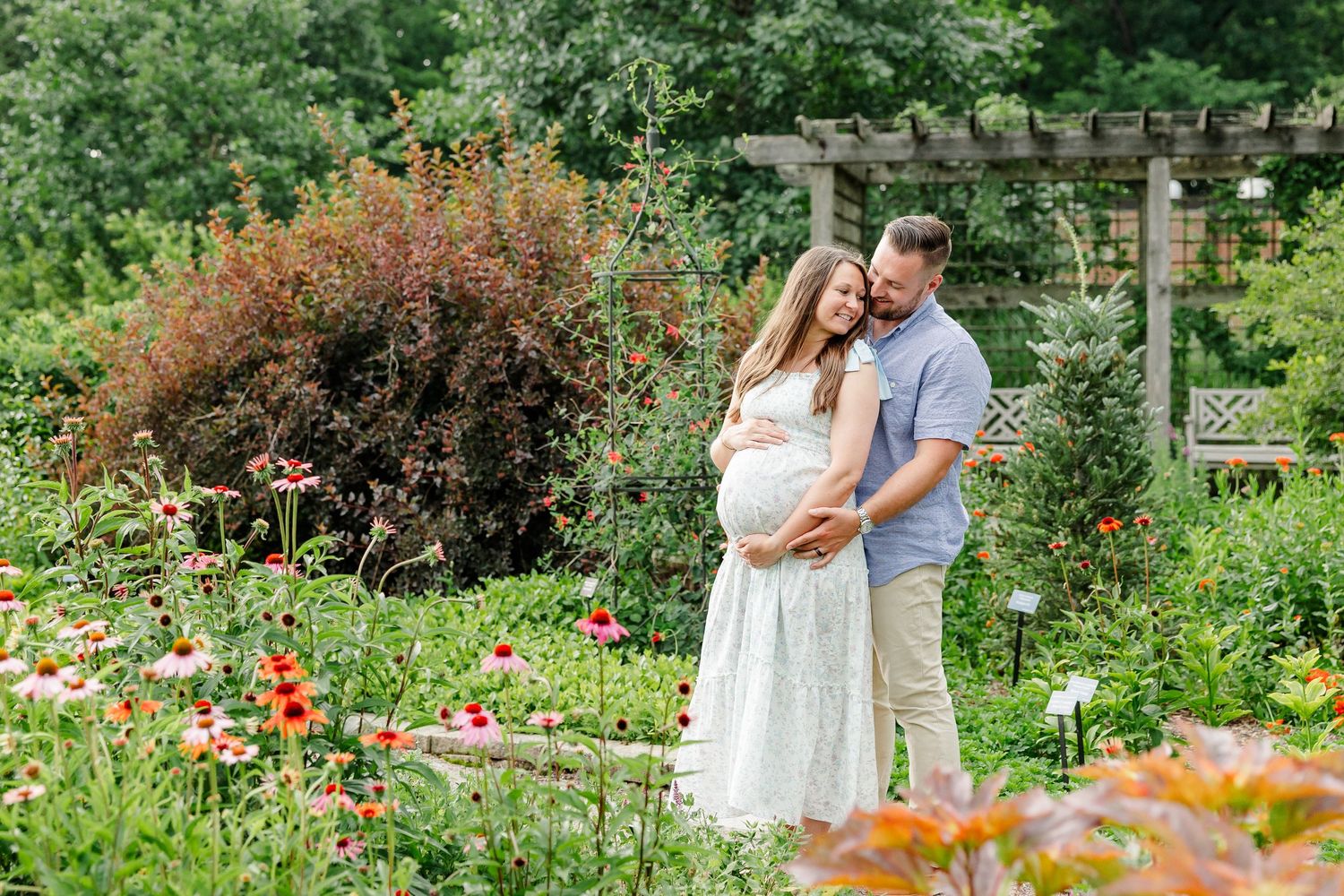 Expecting parents cuddling in colorful summer flowers during a Cantigny Park maternity session