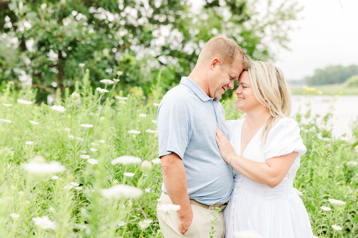 A tender moment between a couple surrounded by white wildflowers in a summer field.