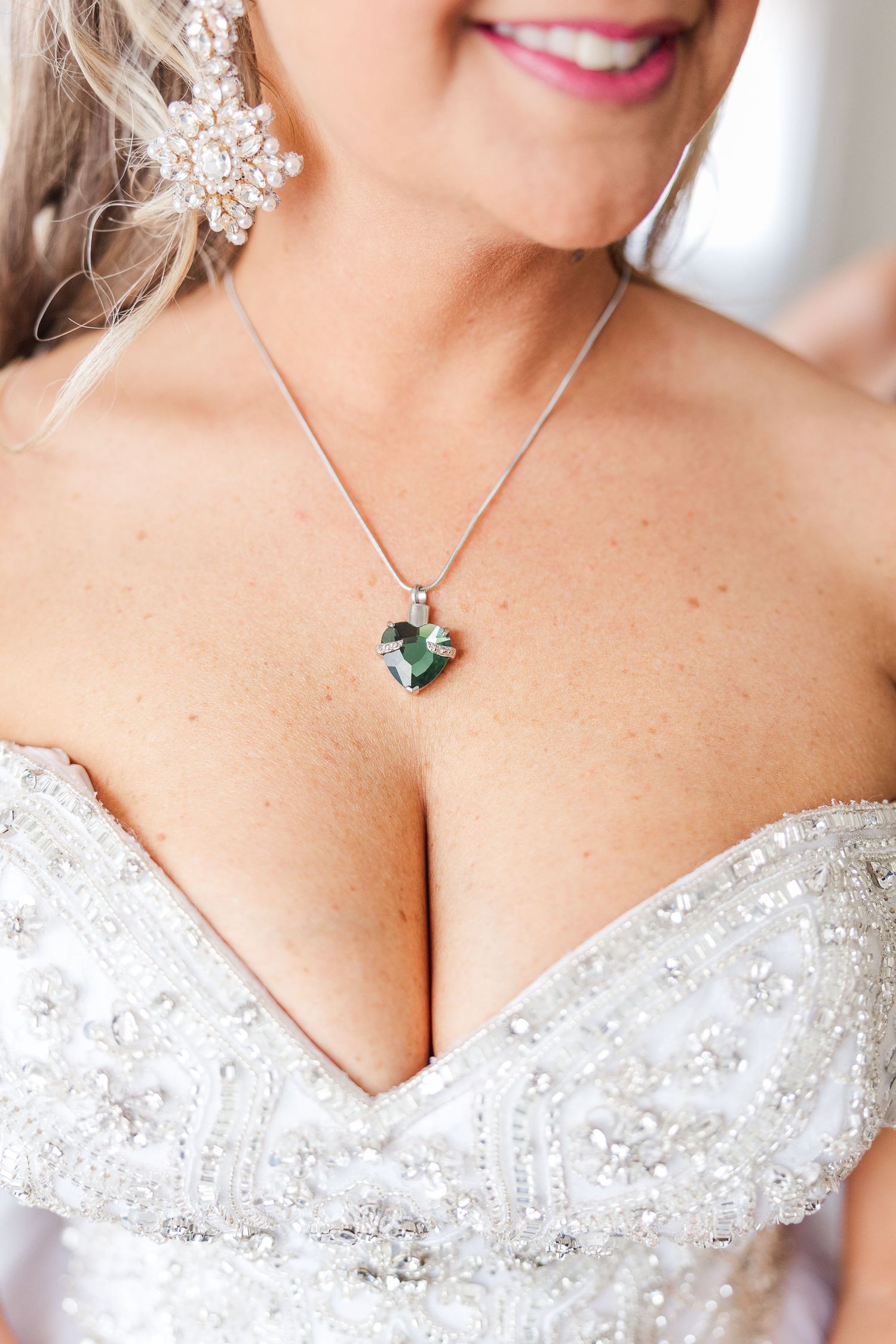 Close-up of delicate bridal jewelry and beaded sweetheart neckline of a wedding gown.