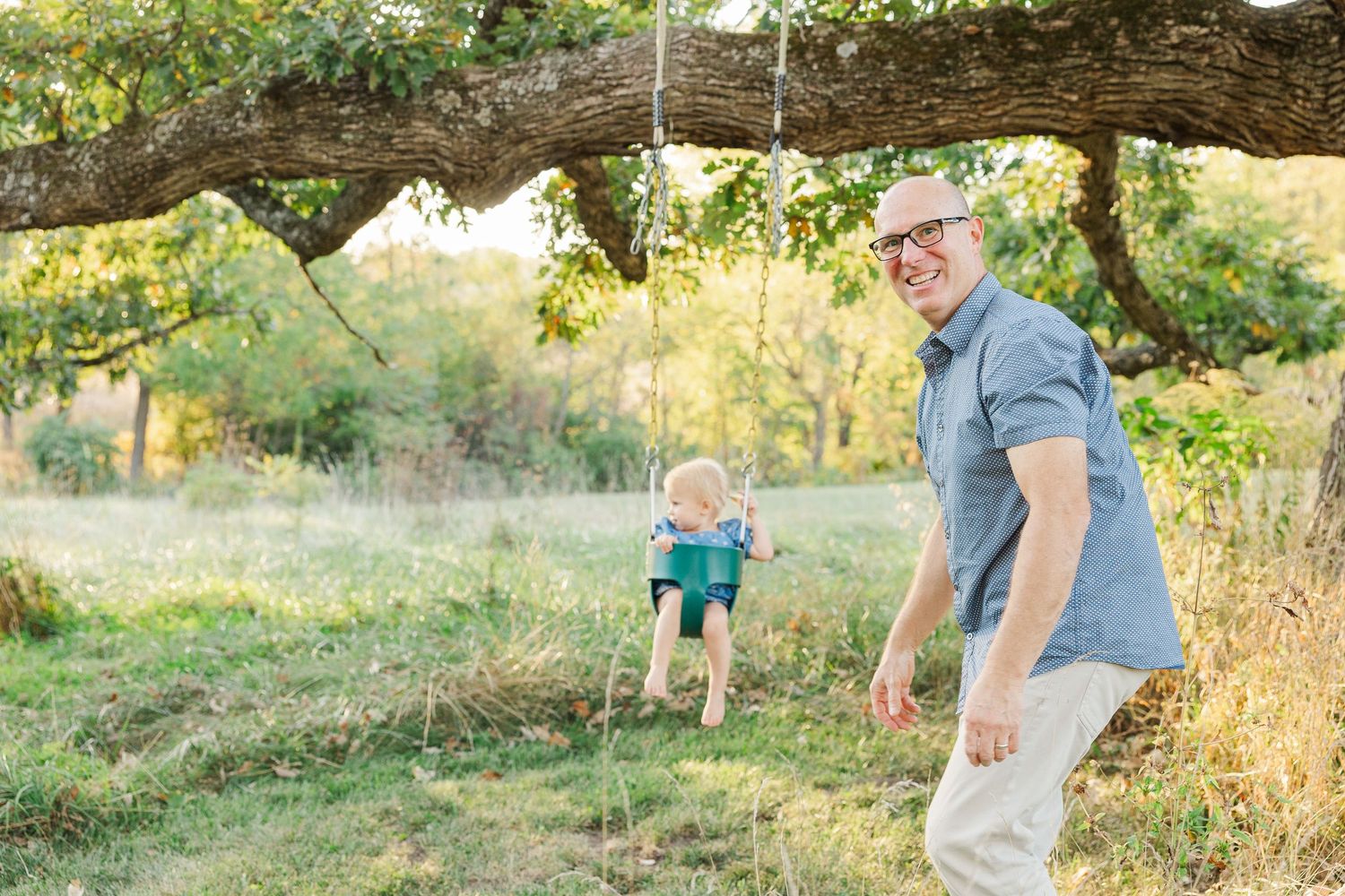 Family members enjoy a playful outdoor photo session in a sunlit field during golden hour.