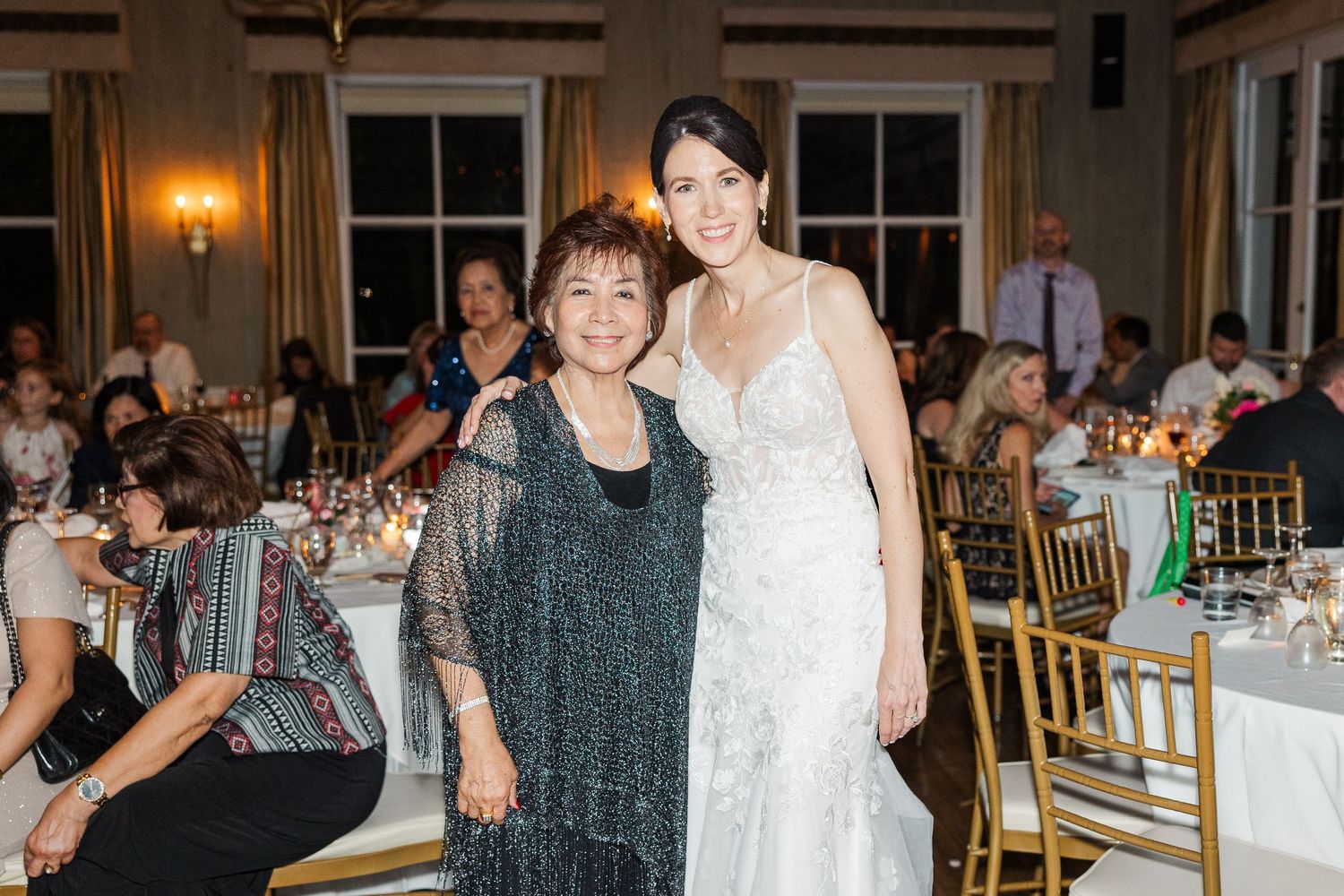 Wedding celebration in an elegant dining room with golden chairs and warm lighting.