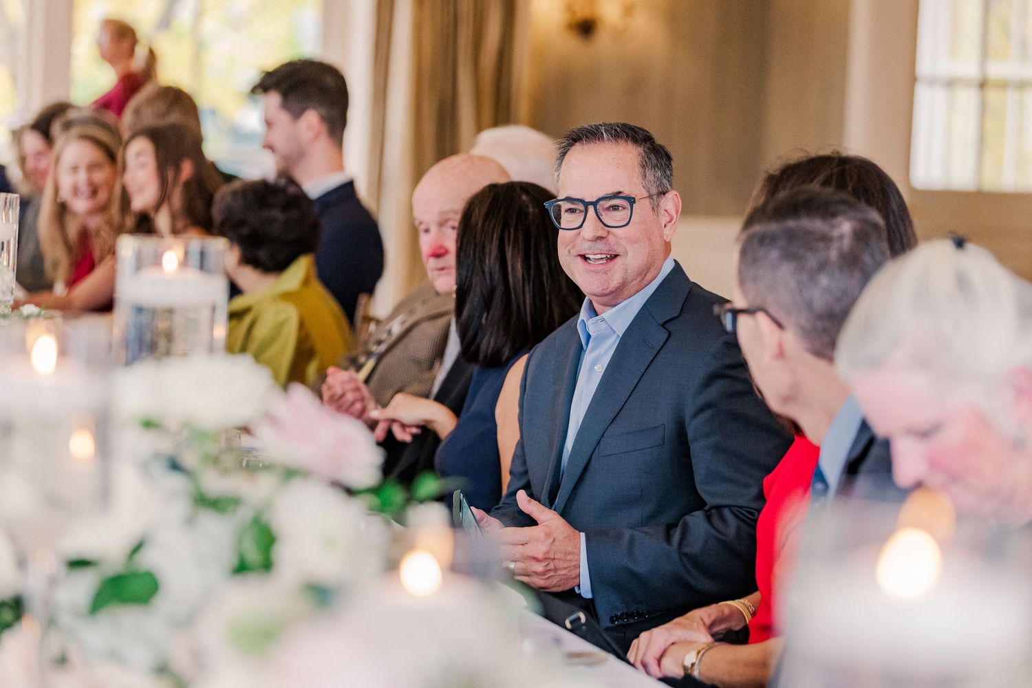 Wedding guests enjoying conversation at an elegant reception dinner with floral centerpieces.