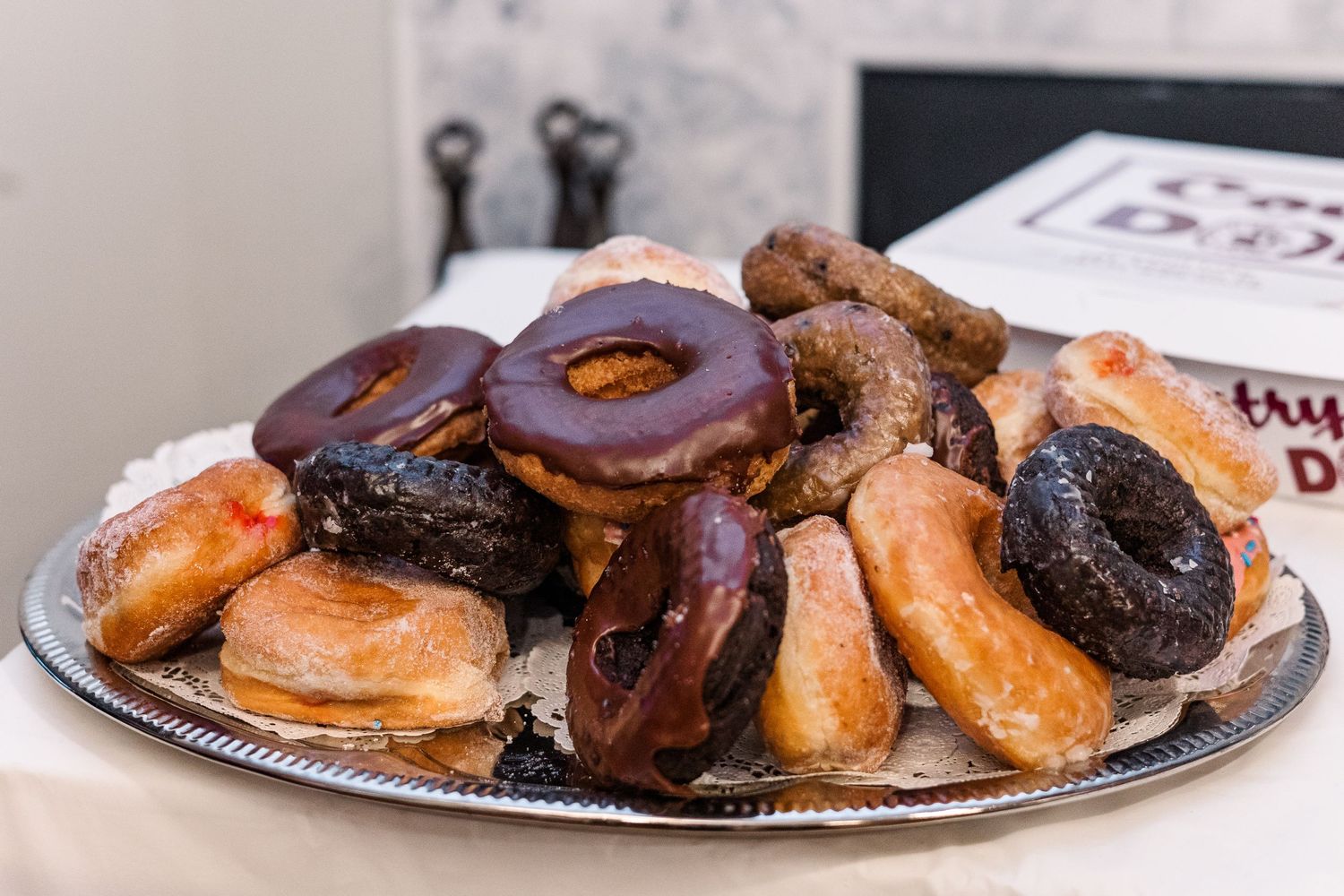 A platter filled with assorted chocolate and glazed donuts served at a celebration.