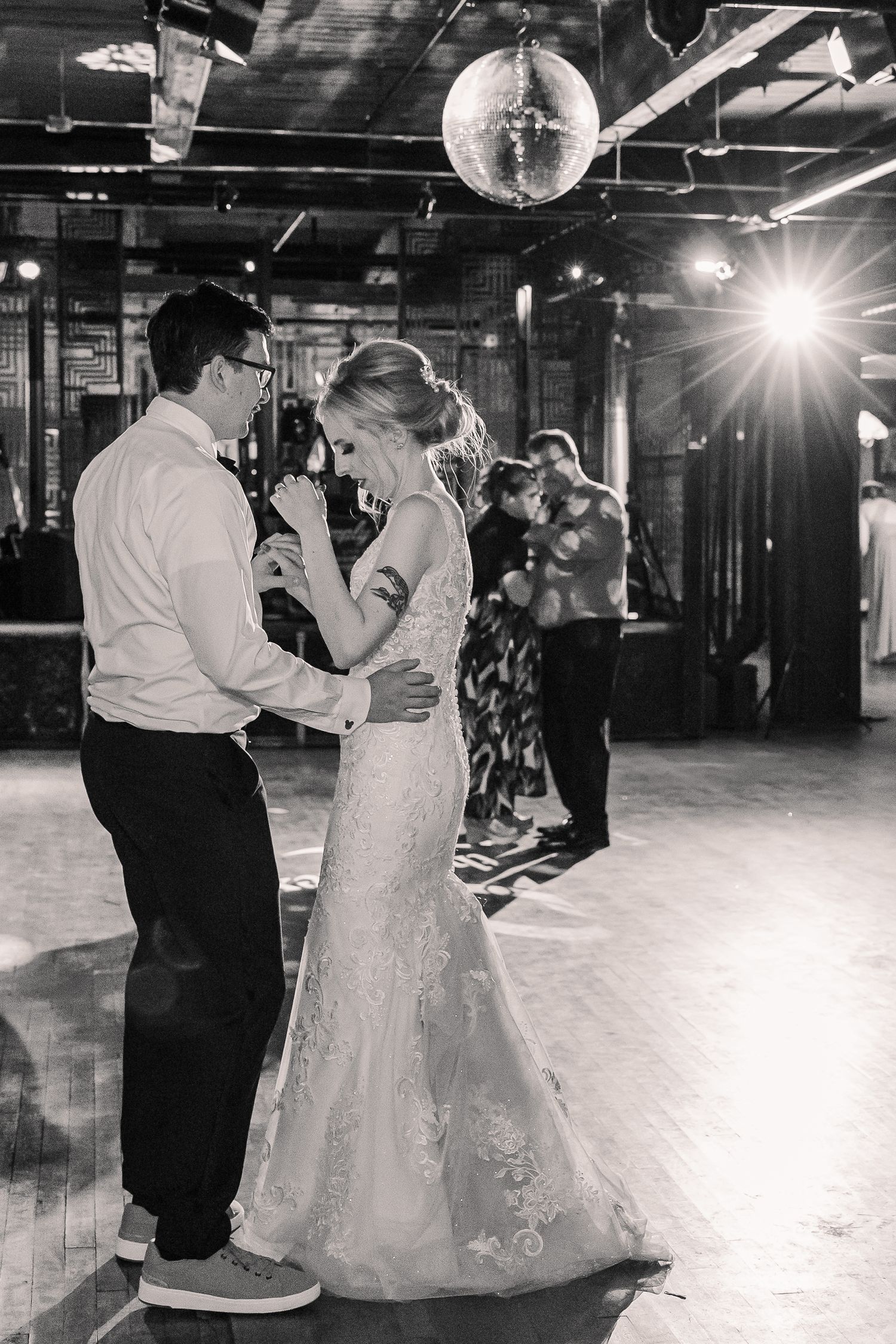 A couple shares their first dance under a disco ball at their wedding reception.