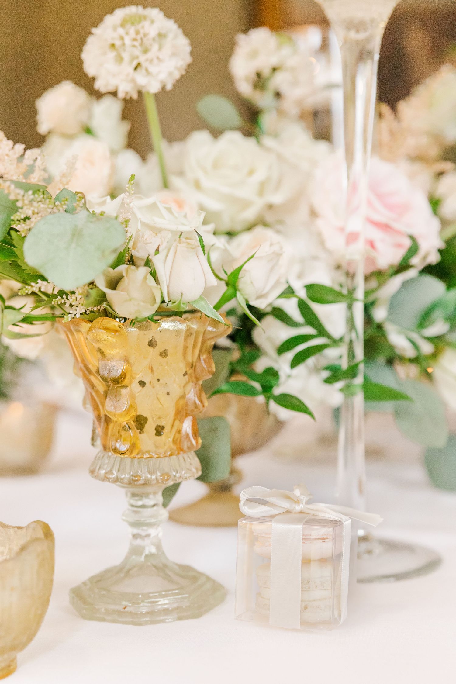 Delicate white and pink roses in a gold-tinted crystal vase with greenery accents.