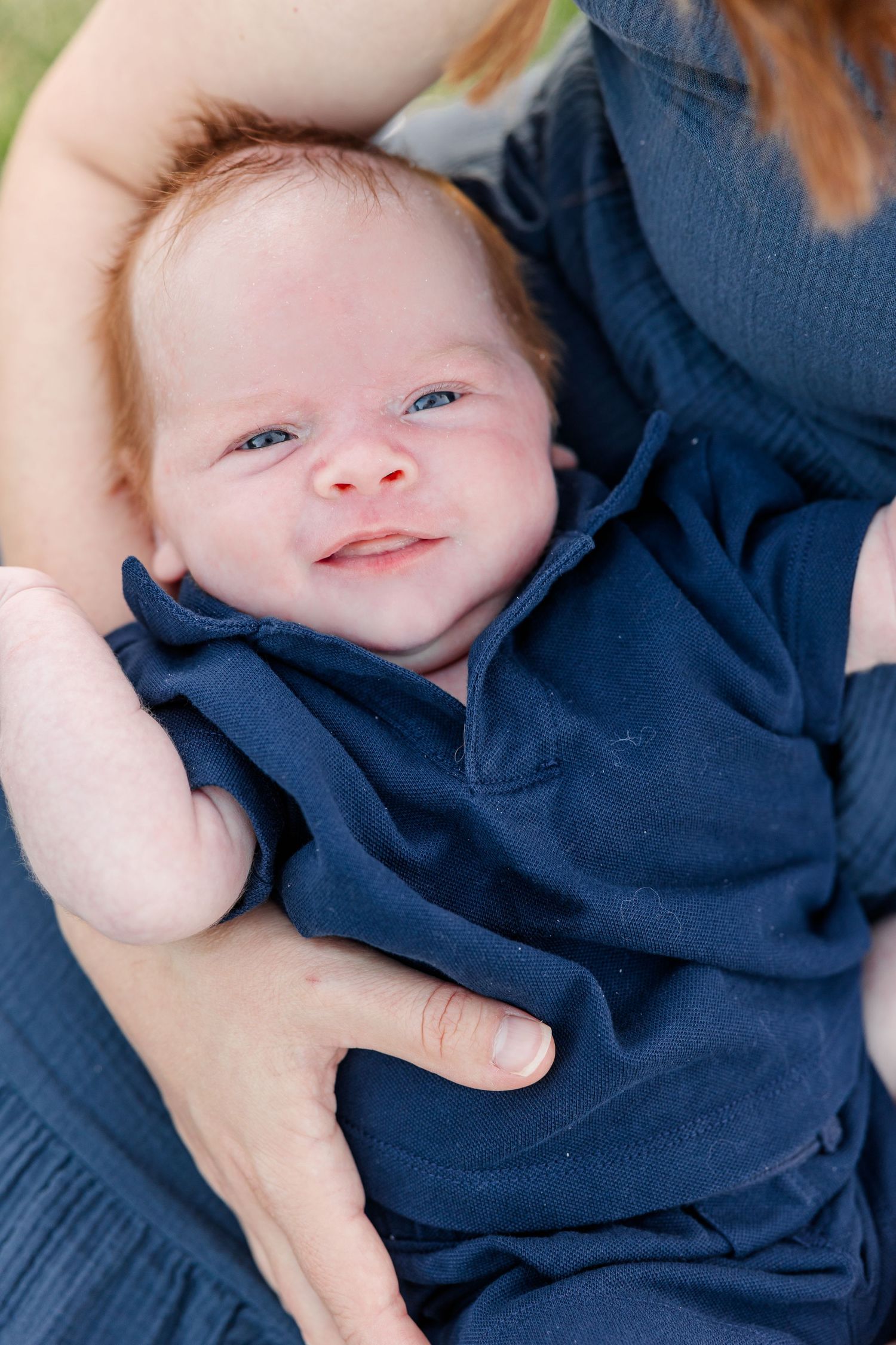 Newborn Lincoln smiling while resting in Hilary’s arms during their Cantigny Park family session.